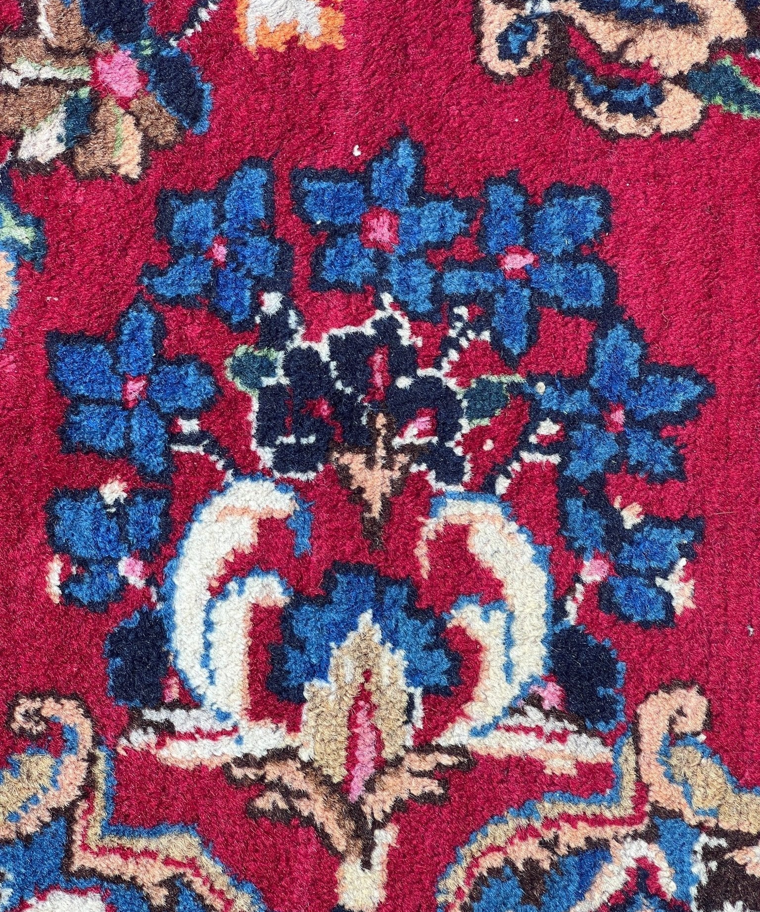 Red rug with blue floral motifs and ivory medallion center, detailed pattern