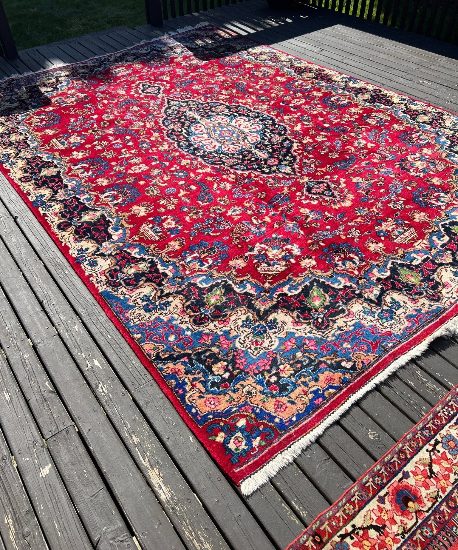 Persian Mashad rug, red field with navy and ivory floral medallion, fringed border