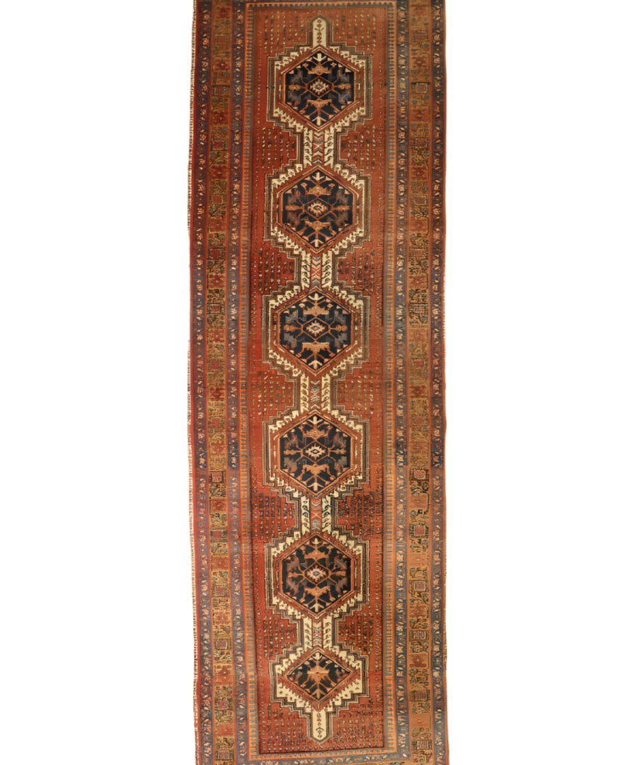 Runner rug with rust background and vertical row of dark navy medallions