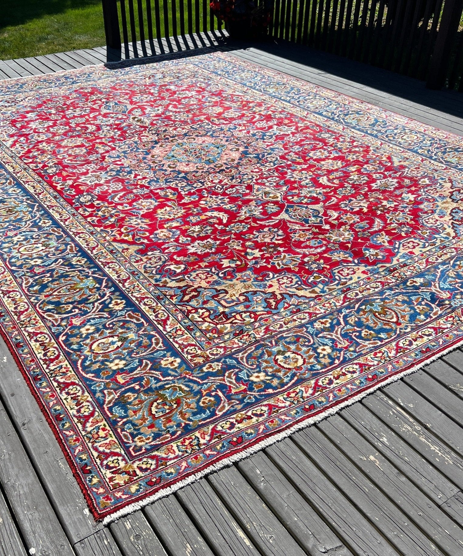 Persian-style rug with red field, blue floral motifs, and ornate multicolor border