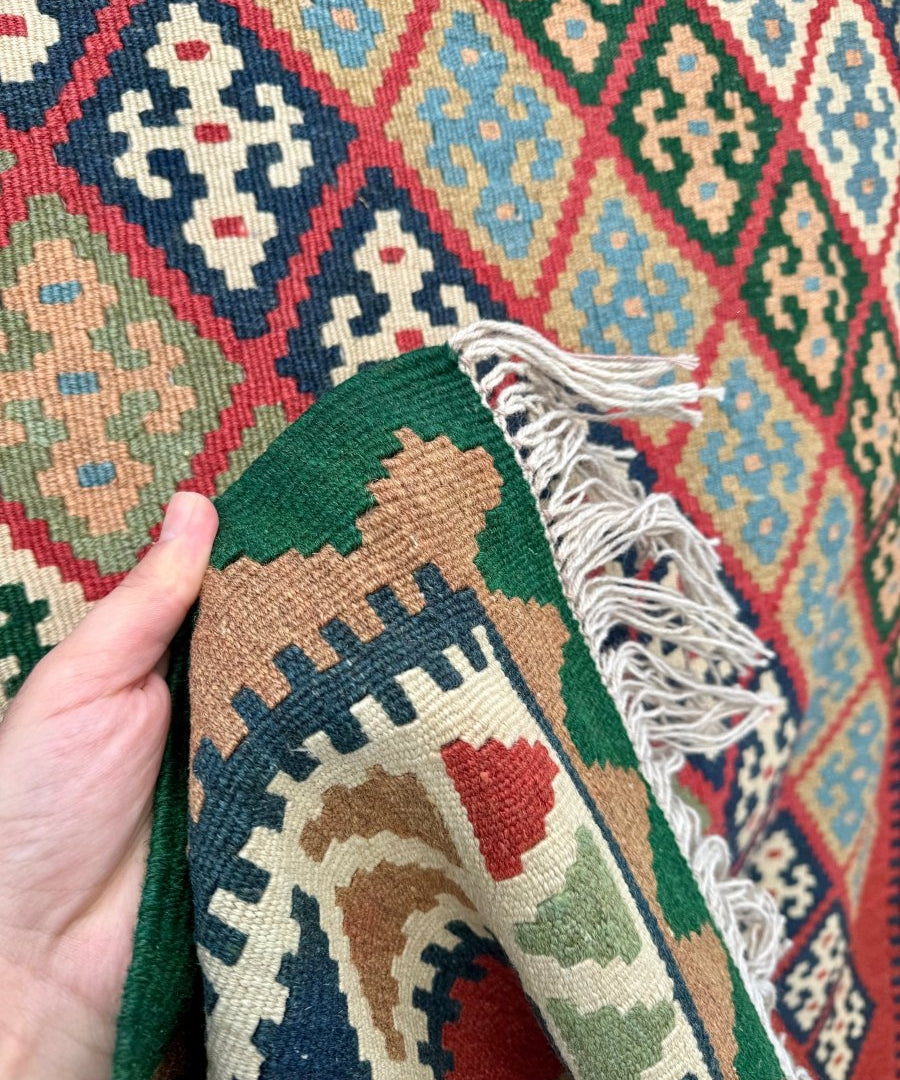 Kilim rug corner detail with multicolor weave, tan border and short white tassel fringe