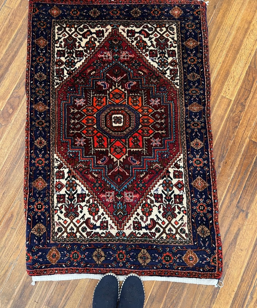 Persian Qoltoq rug: dark navy border, red central medallion, geometric motifs