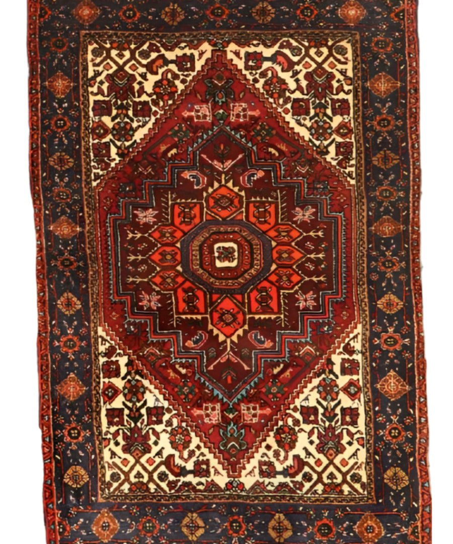 Rug with warm red center medallion, ivory diamonds, dark navy frame, full view