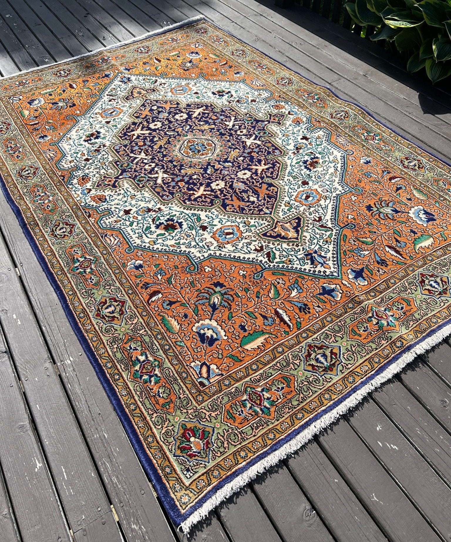 Patterned area rug with orange, navy, and cream medallion, bordered edge