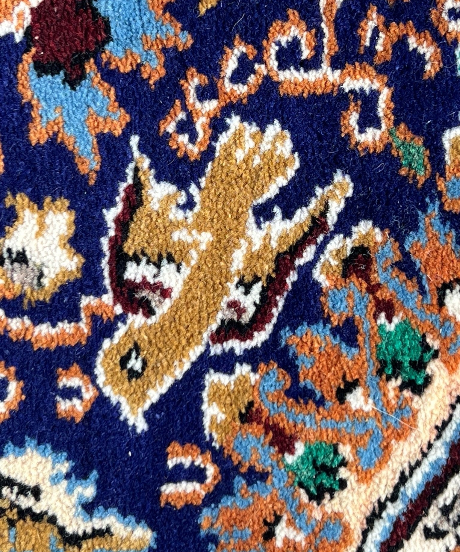 Close-up patterned rug section with navy field, gold shapes, teal and orange accents