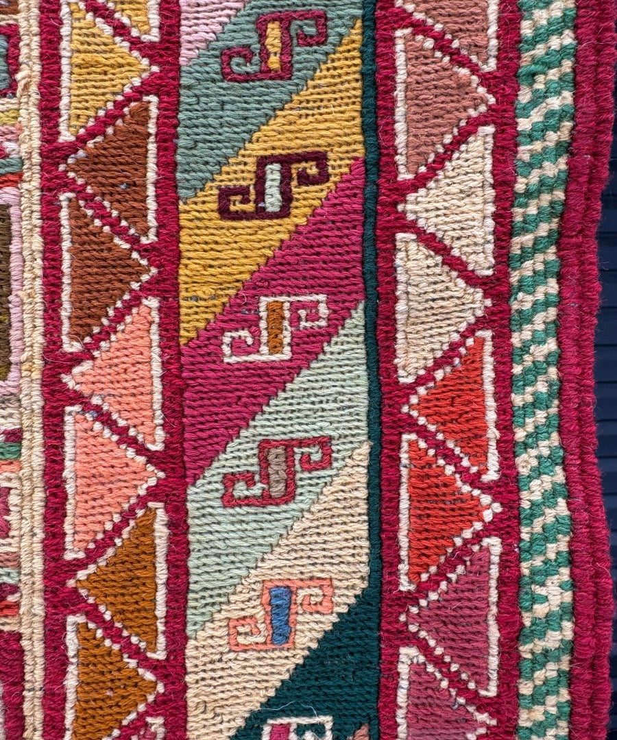 Kilim rug close-up with zigzag motifs and multicolor woven sections in red, teal, yellow