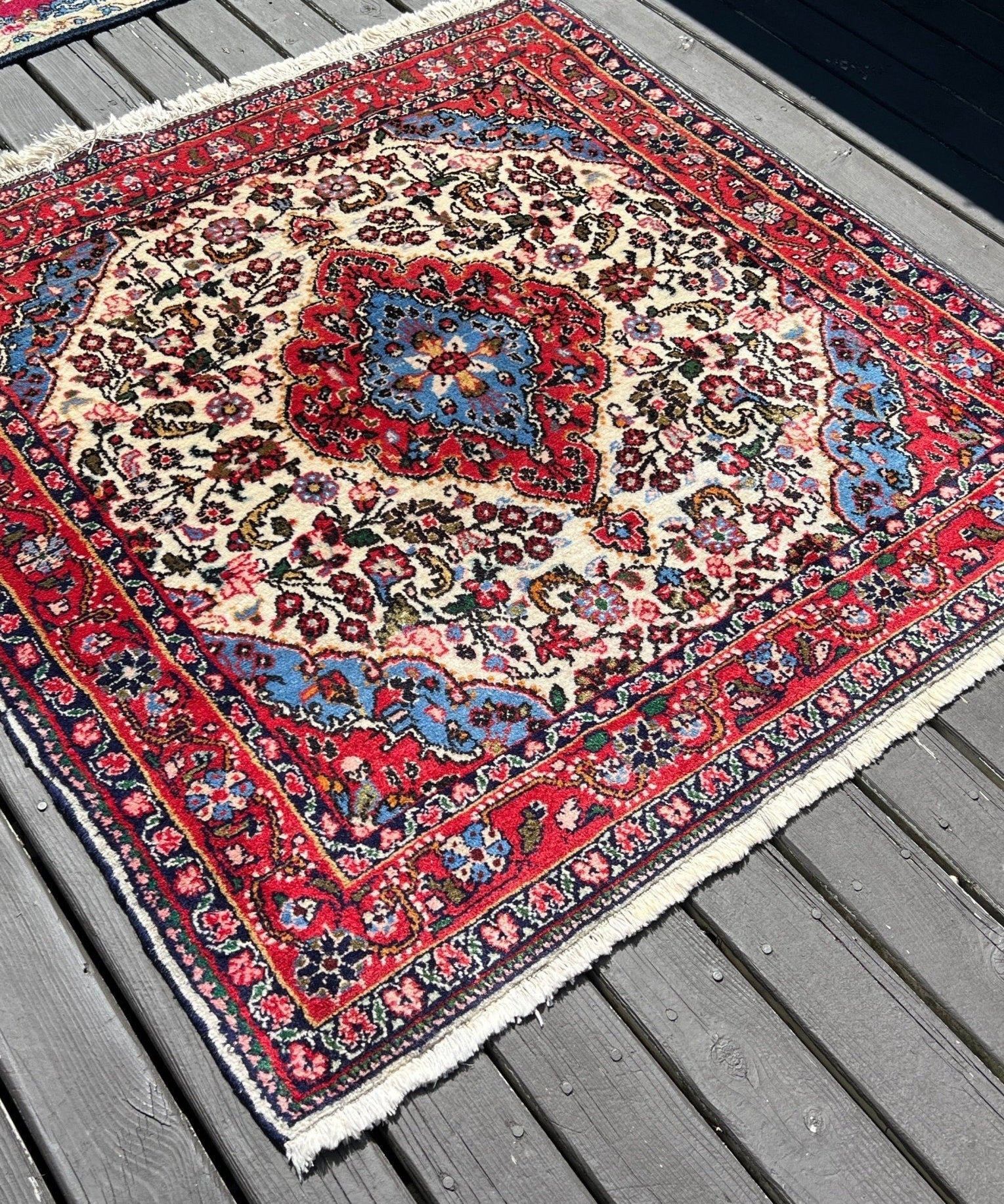 Persian rug with cream floral medallion, red border and blue accents