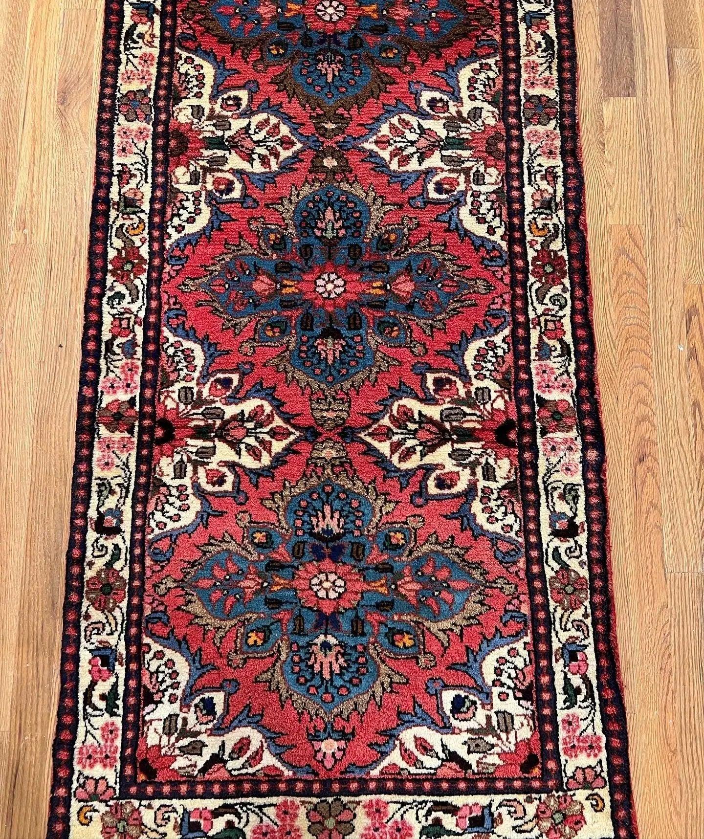 Runner rug with dark red field, blue floral medallions, and cream patterned border