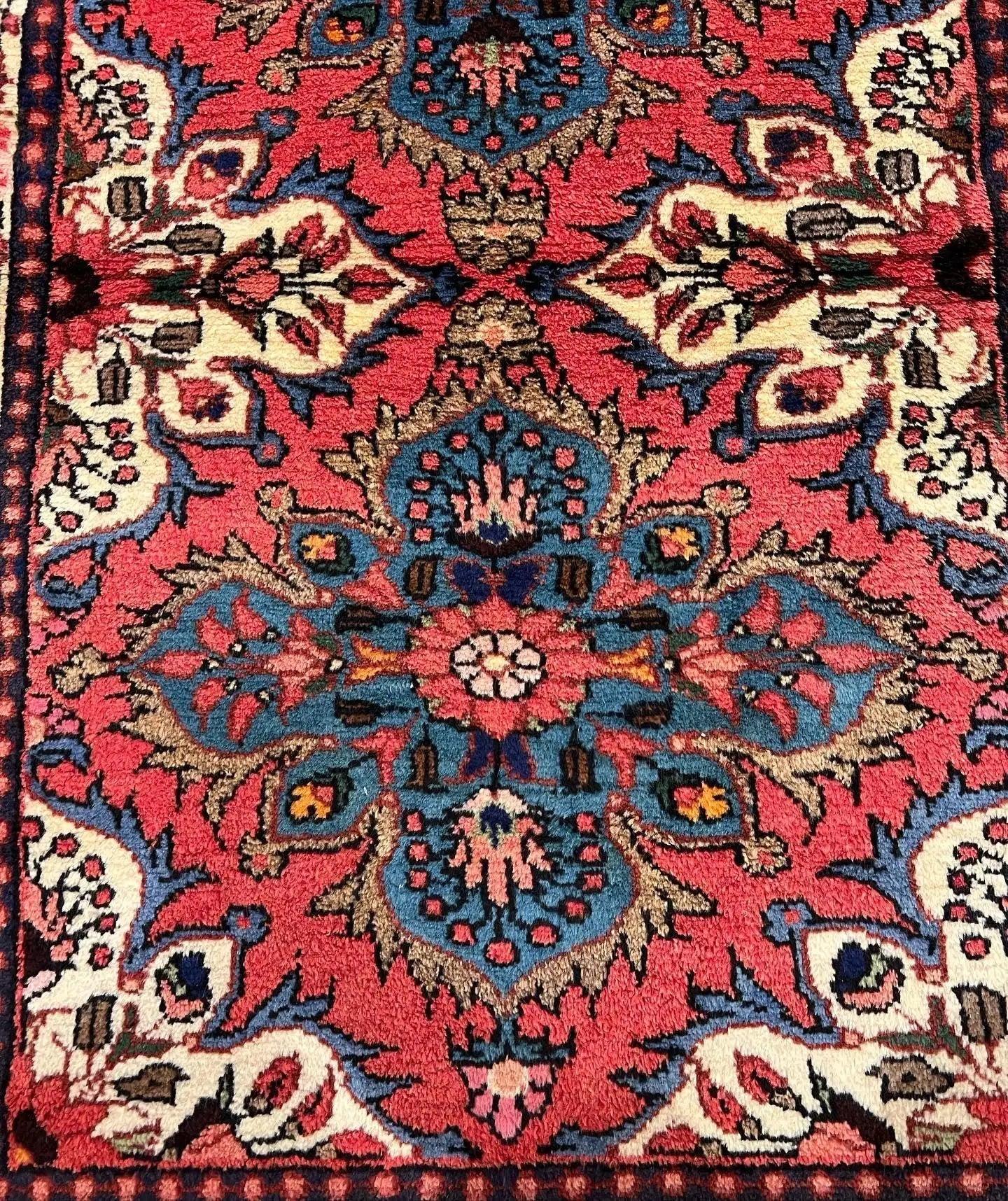 Red runner rug close-up with navy and blue floral medallion pattern and cream accents