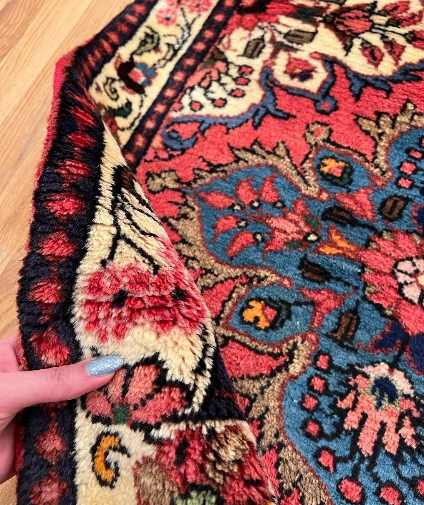 Close-up of runner rug texture with red and blue floral motifs and cream details