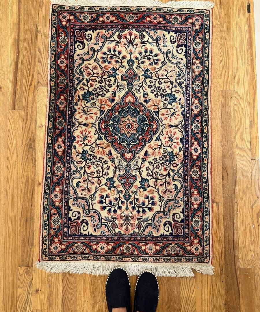 Sarouk rug, cream center with dark medallion, blue/red floral border and short fringe