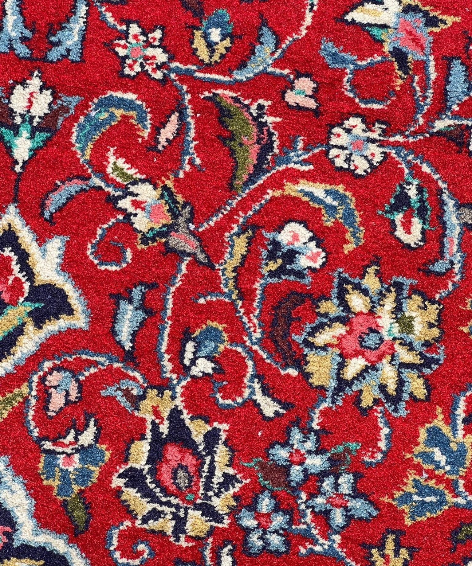Sarouk rug pattern detail: red and blue floral motifs with cream accents
