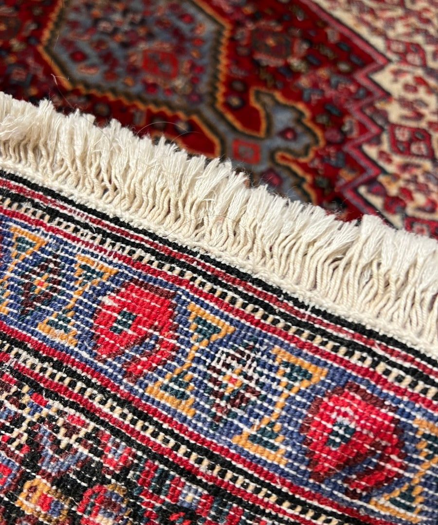 Persian-style rug fringe edge, cream fringe with red and navy geometric pattern
