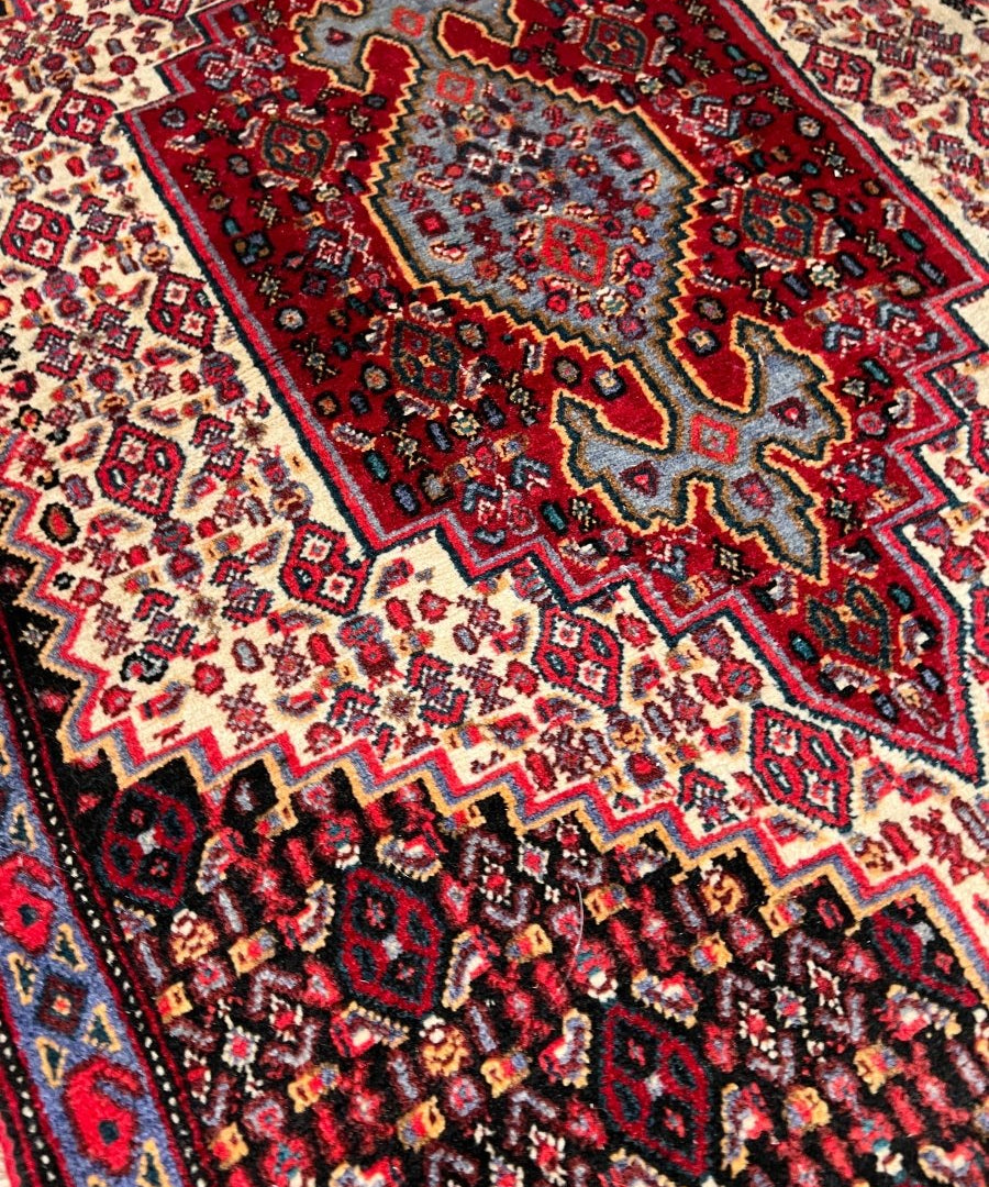 Persian-style rug close-up, red field with cream lattice and blue accents