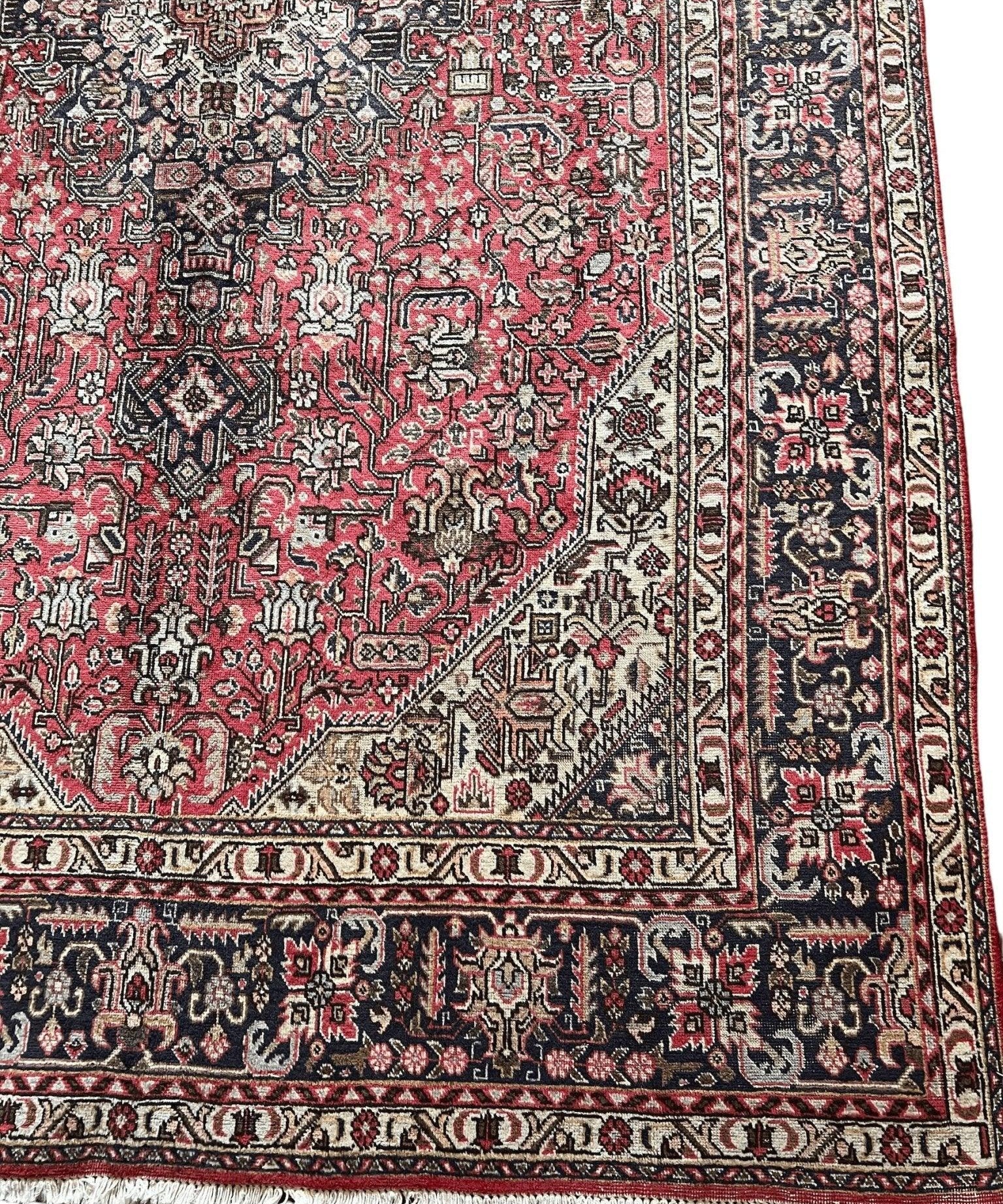 Persian rug close-up with red lattice motifs and dark navy border with repeating details