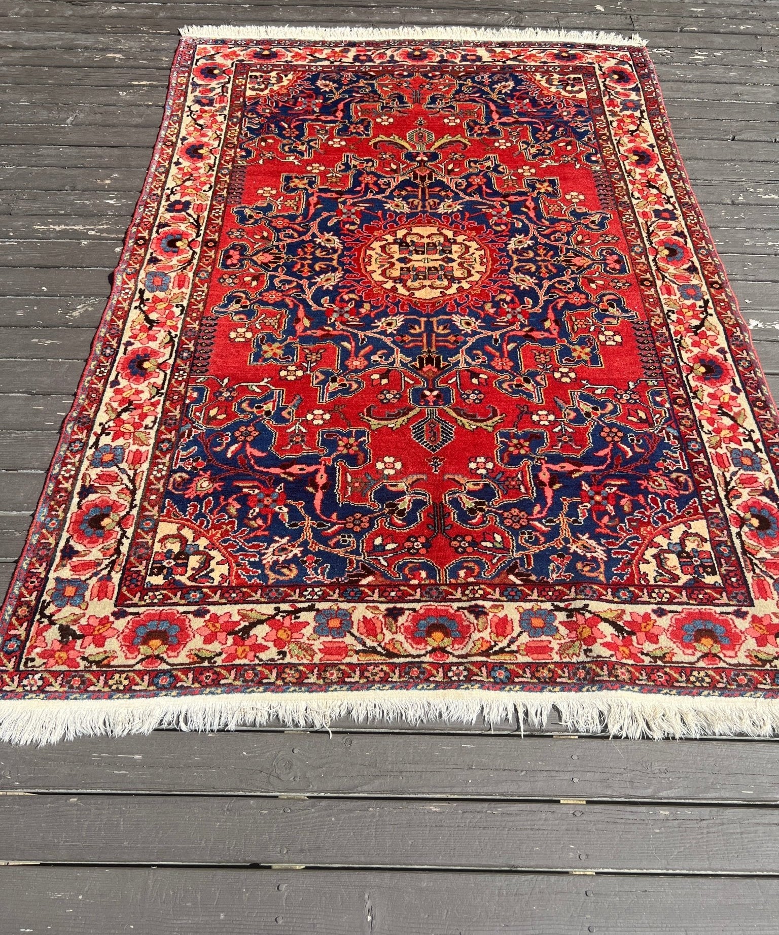 Persian Tafresh rug with red and navy medallion center, cream border, fringed edges