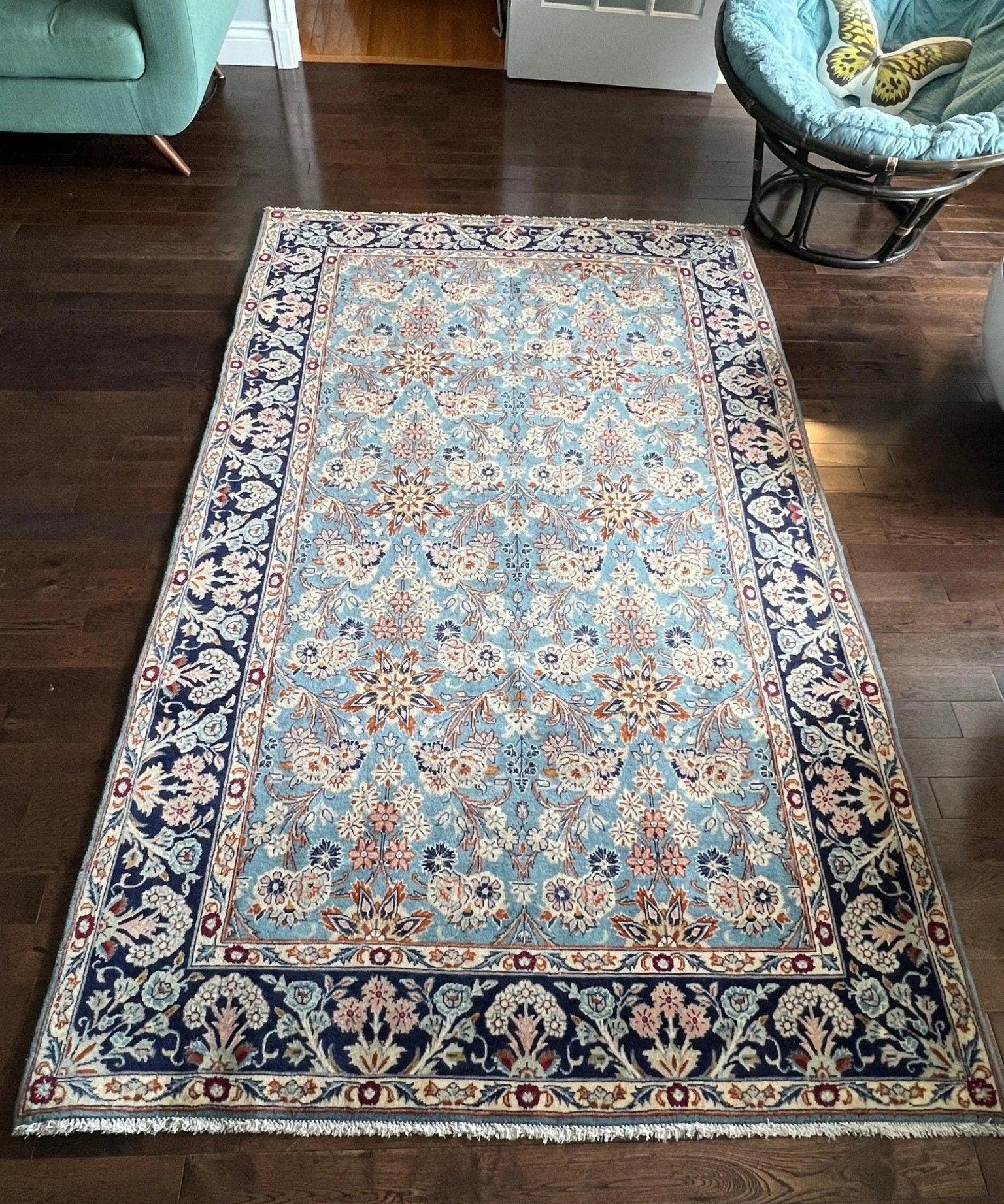 Persian rug in light blue with dark navy border and dense ivory floral center, full view