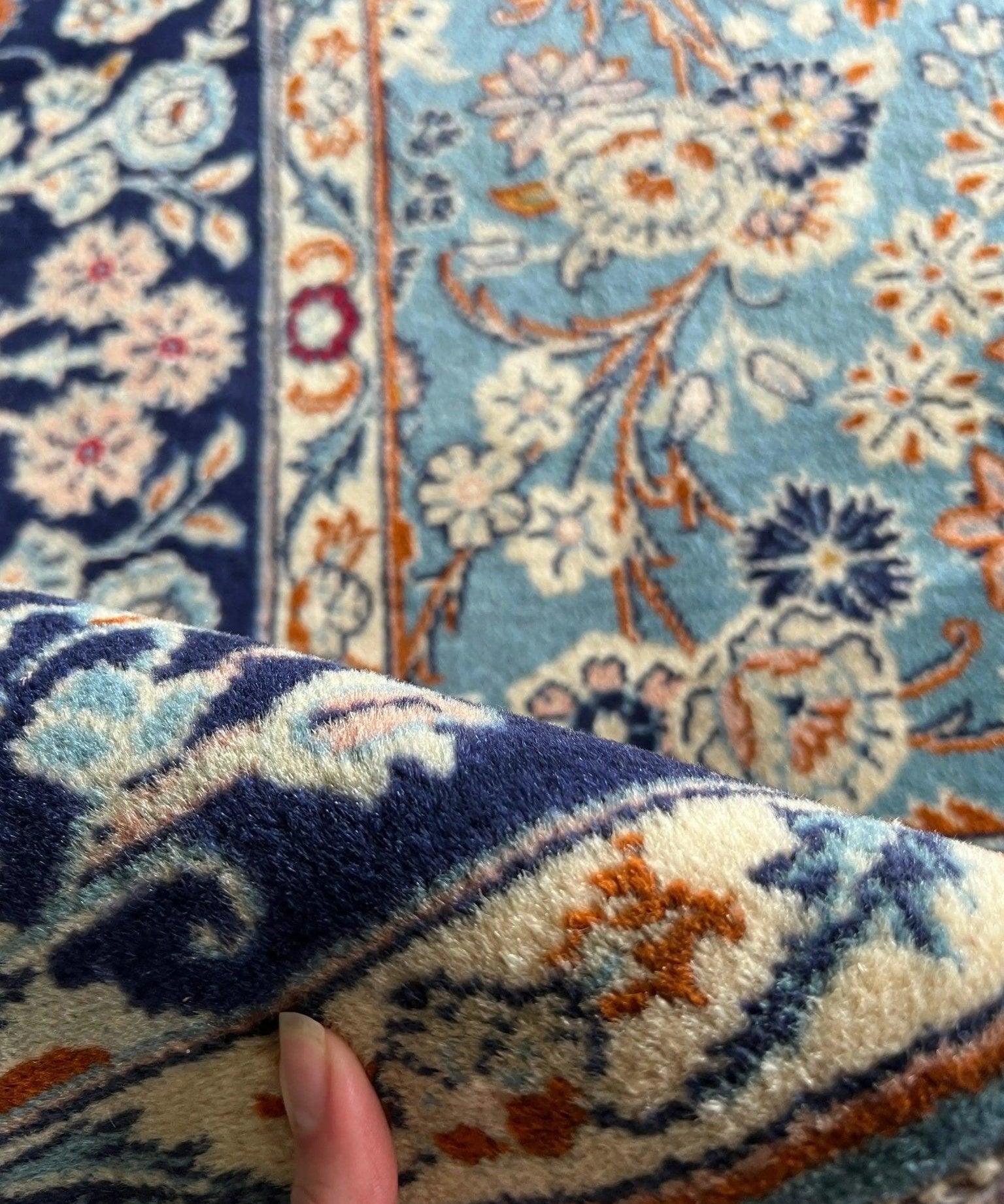 Persian rug corner detail in light blue and navy with multicolor floral motifs