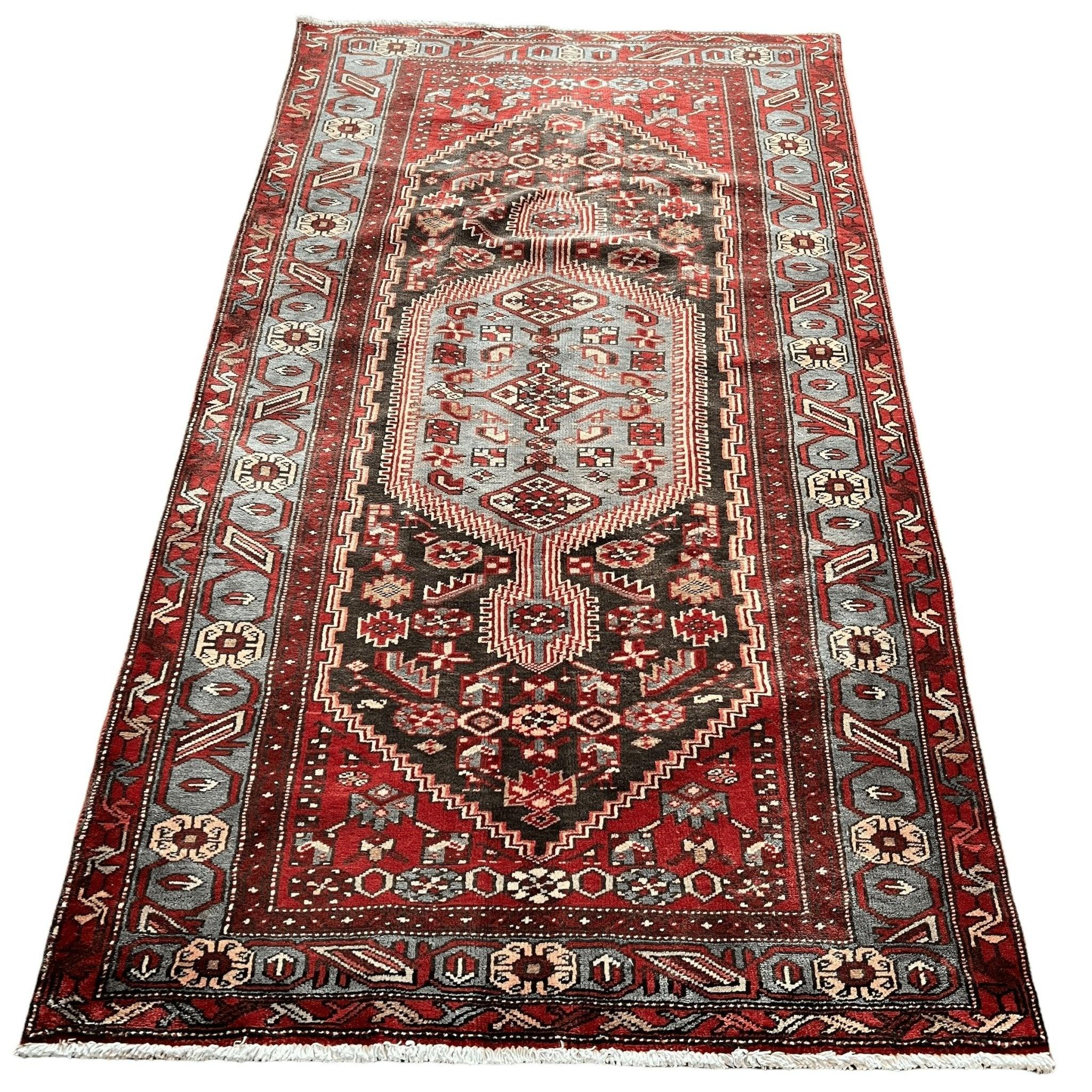 Rectangular Persian Zanjan rug with red and dark accents, cream center, ornate border