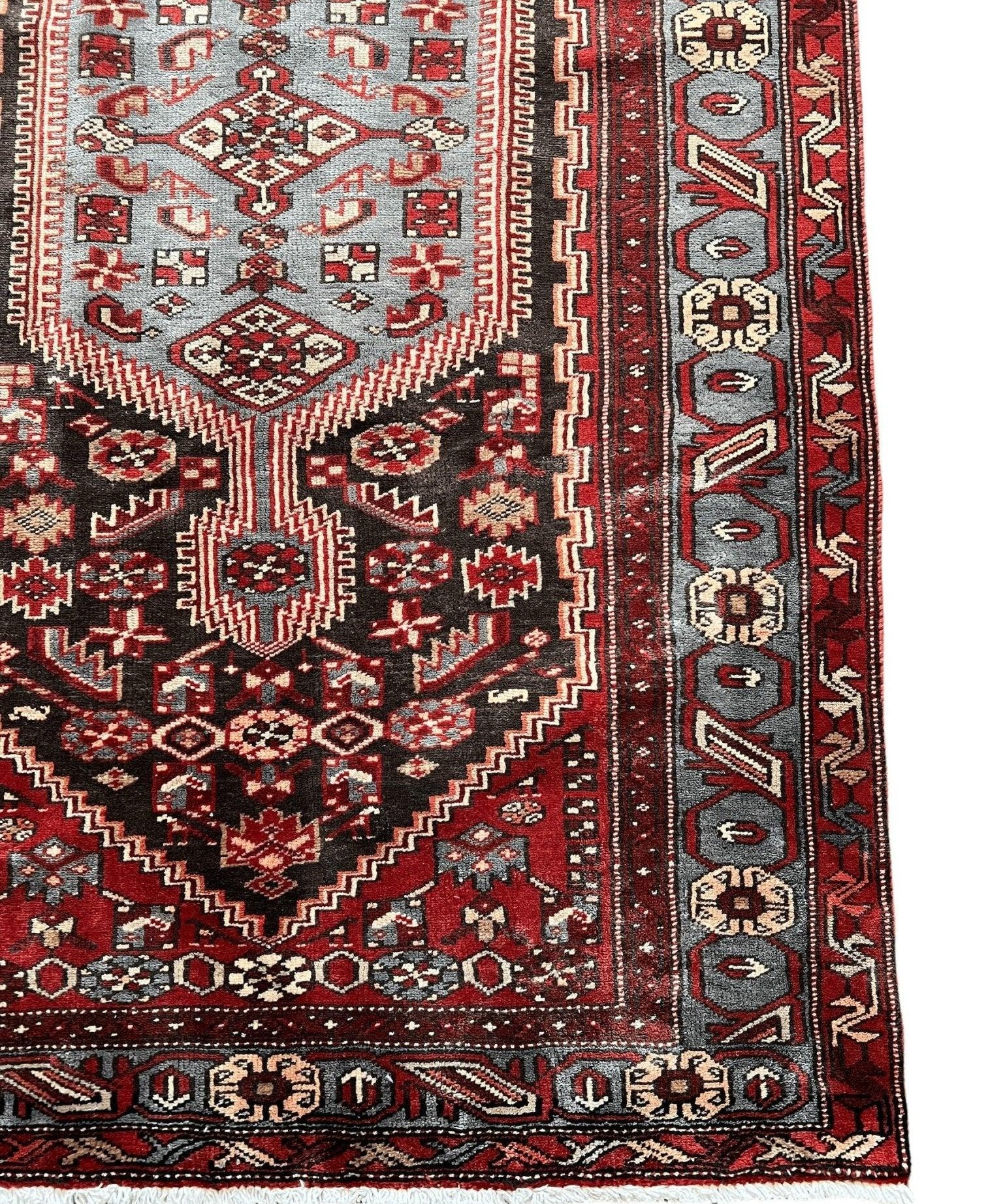 Persian Zanjan rug close-up: cream medallion on red with diamond and stepped motifs