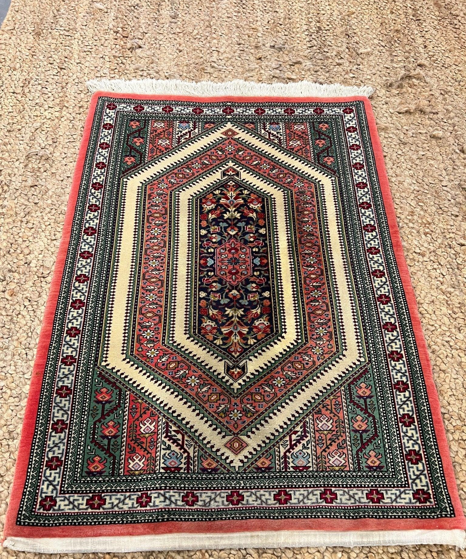Multicolor Persian-style rug with dark navy inner medallion, red frame, and cream accents