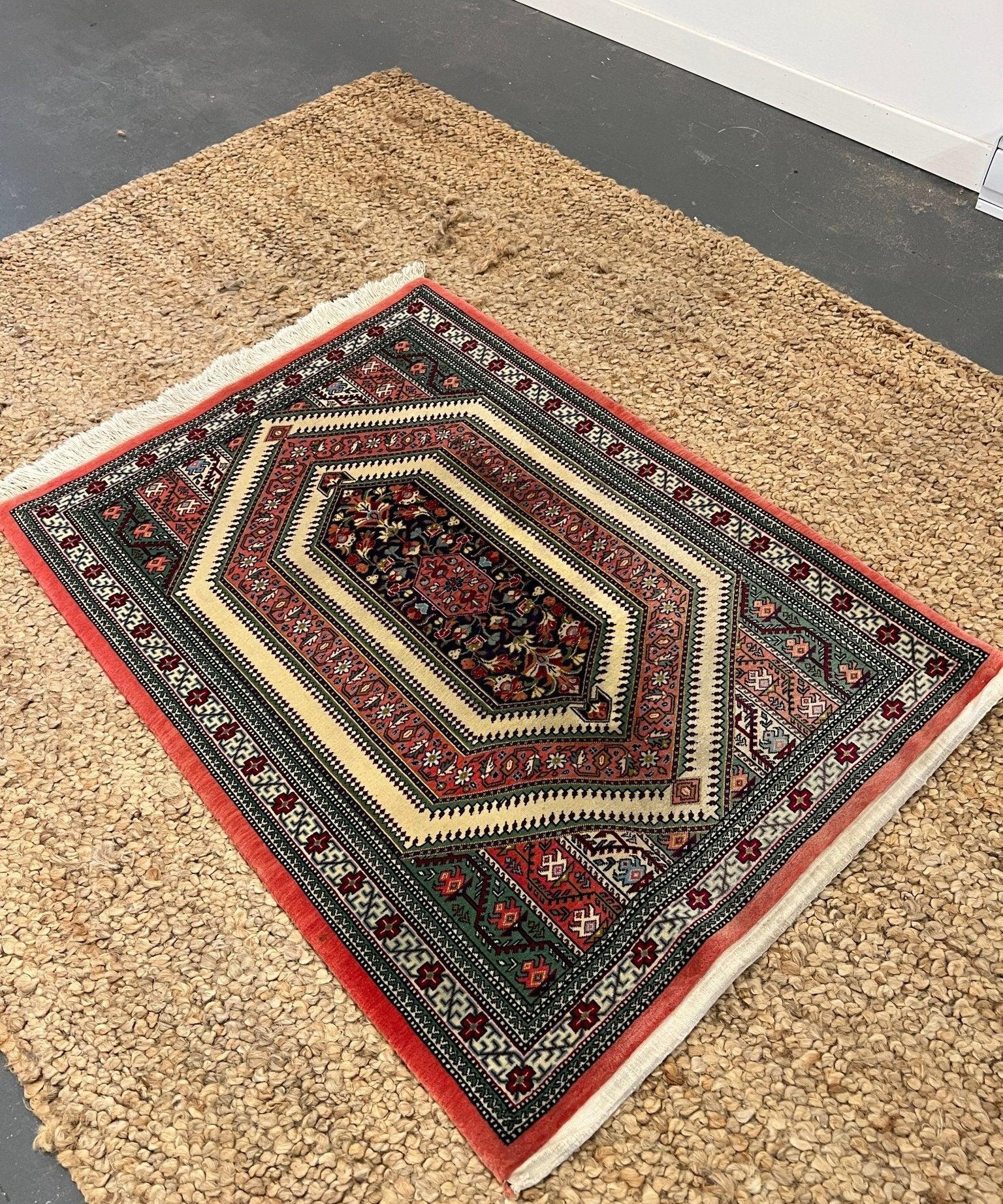 Multicolor Persian-style area rug with red border, cream center, and geometric medallion