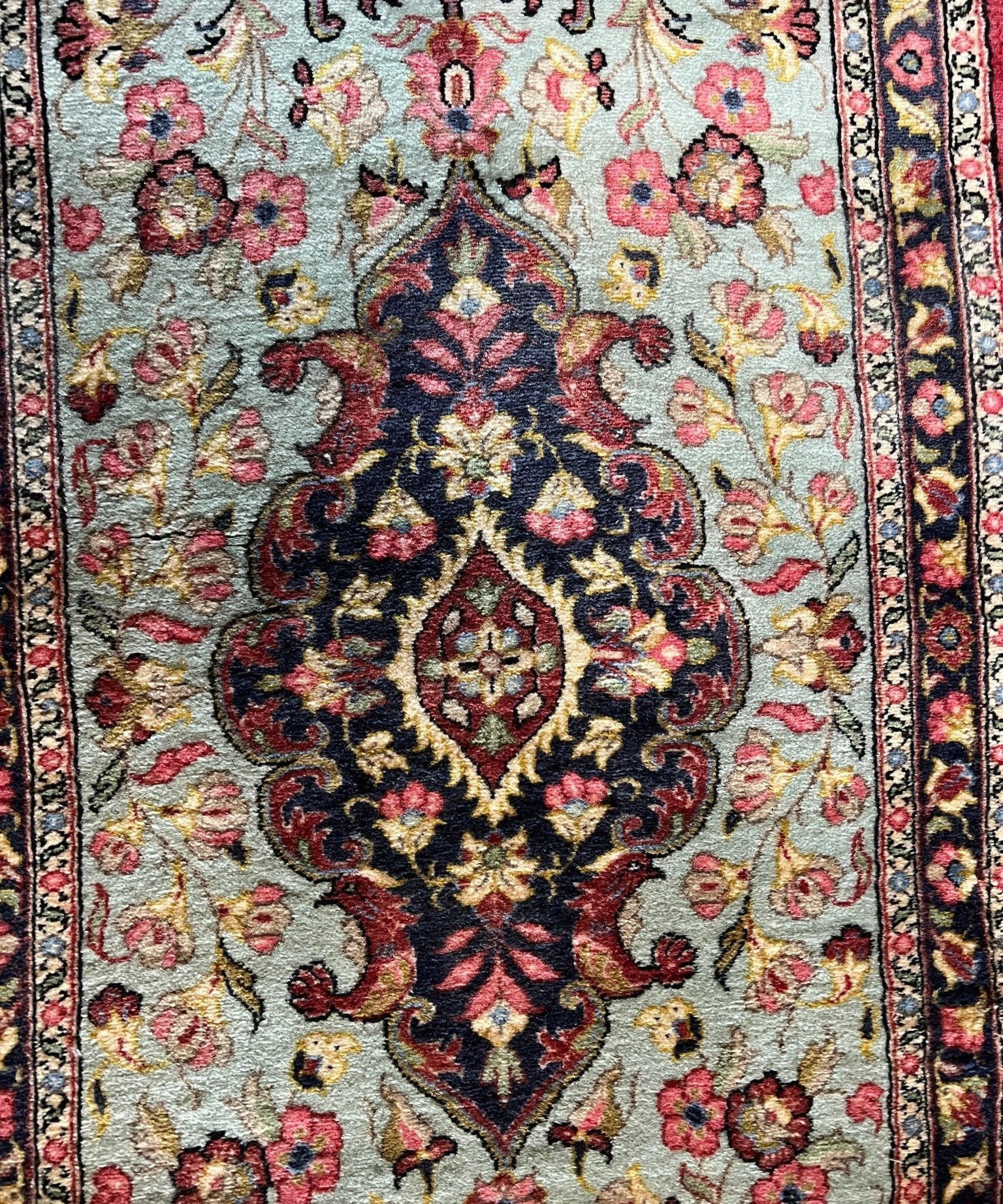 Persian Qom runner rug close-up of floral field and central motif, light blue