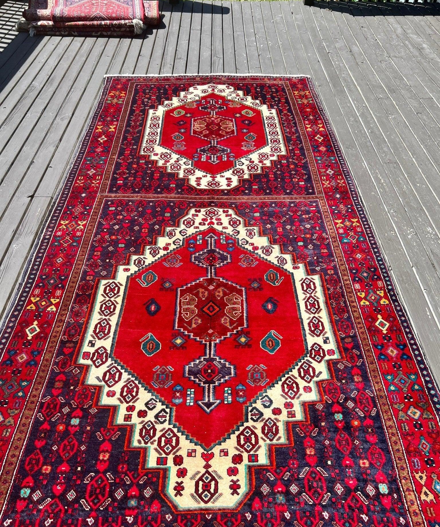 Vintage Senneh rug with red field, cream medallions, and dark navy border pattern