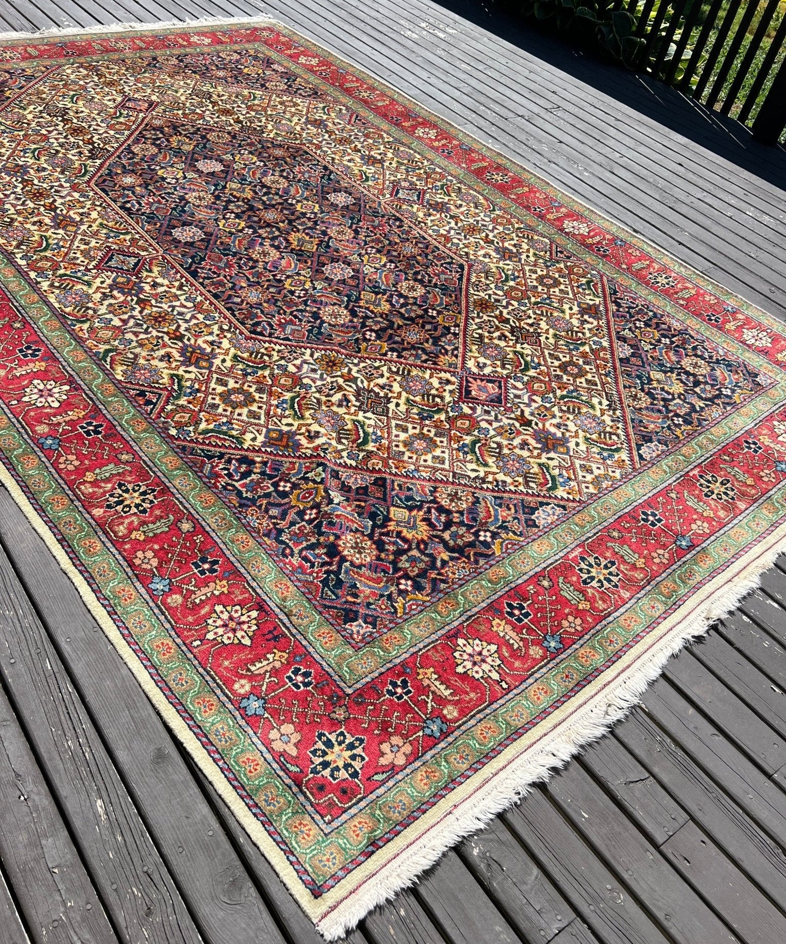 Multicolor Persian-style rug with red border, dark blue central medallion, corner motifs