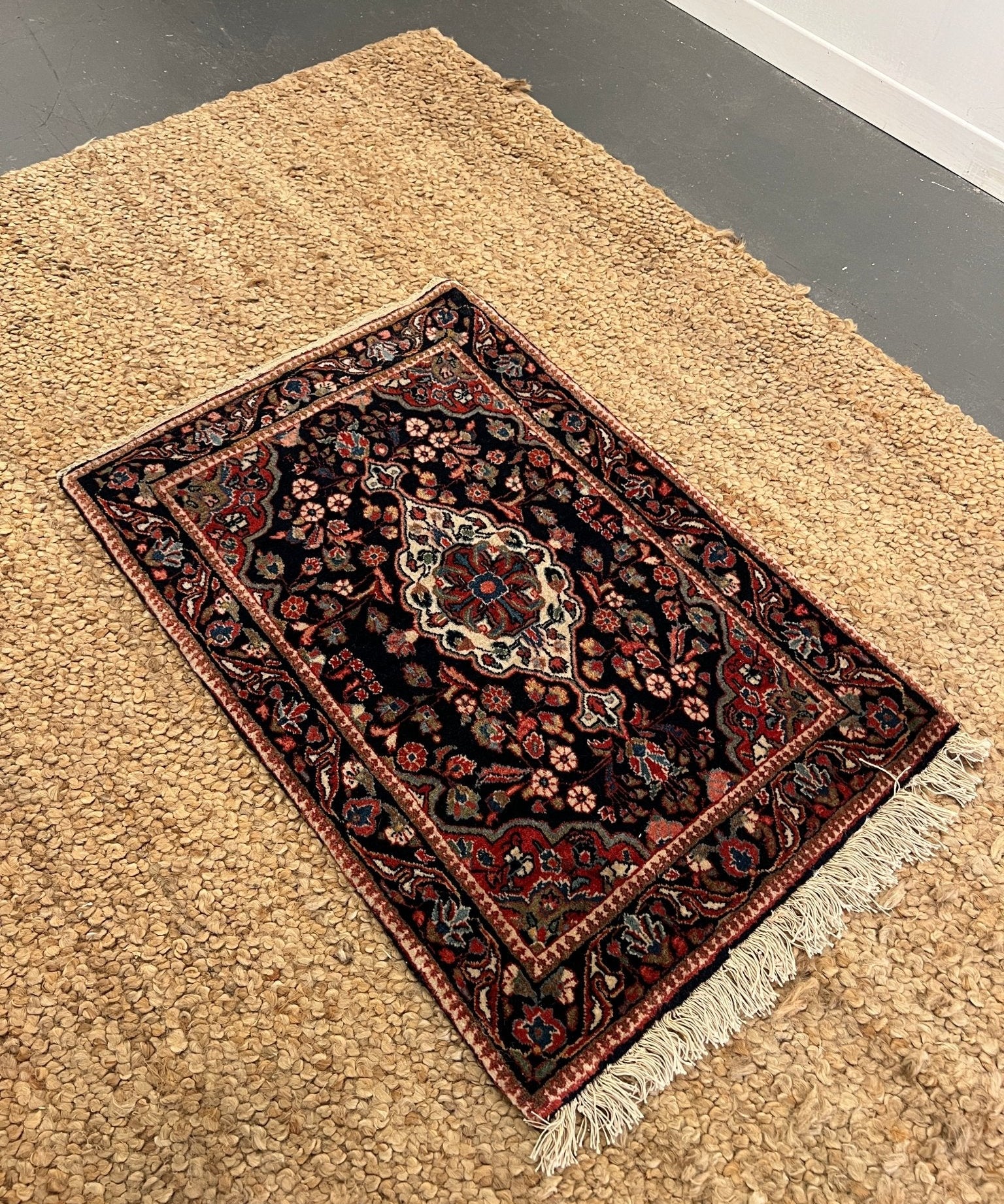 Narrow rug with dark navy center medallion and red blue border, short fringe