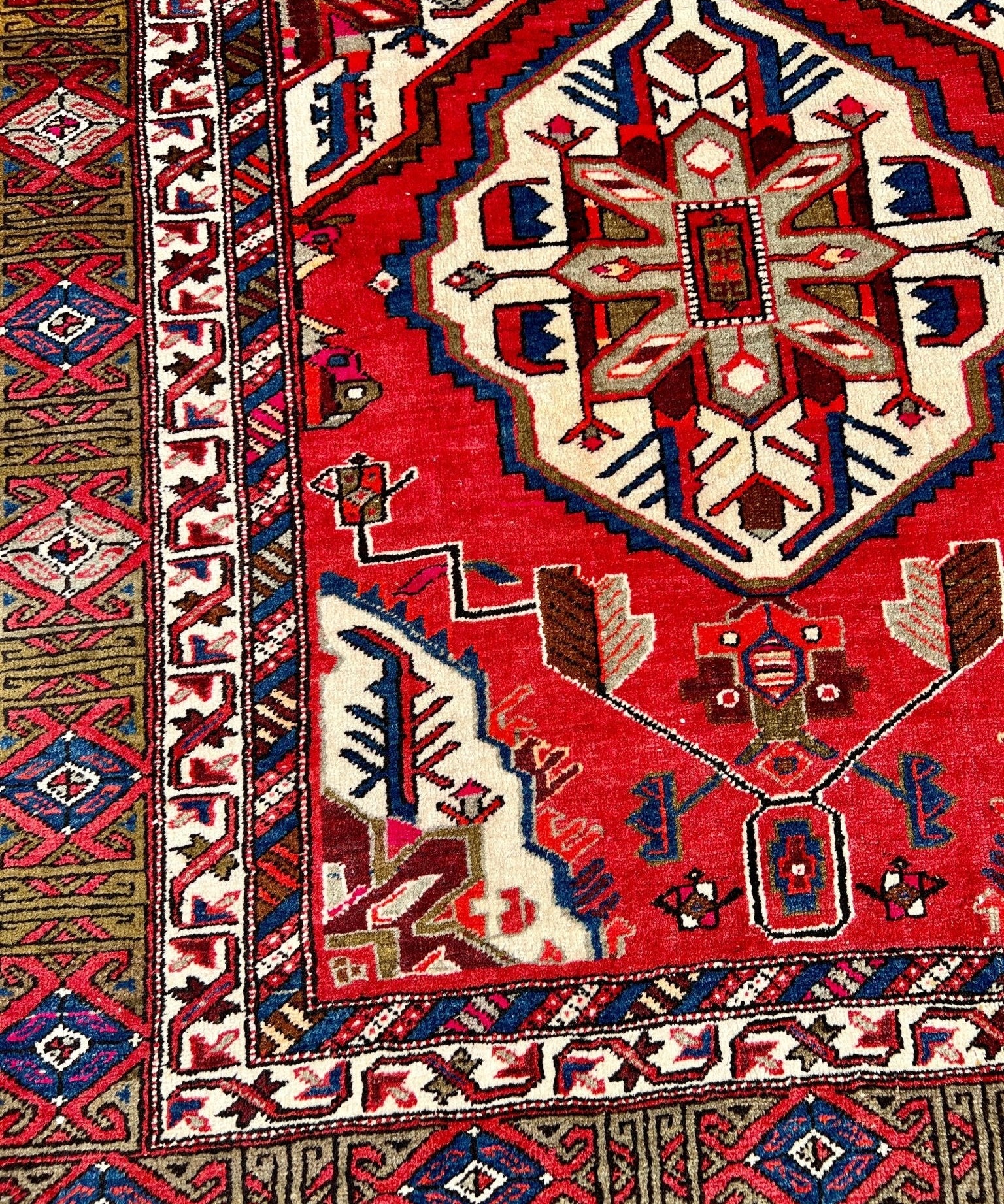 Vintage Persian Meshkin rug detail, red background with cream, blue and diamond motifs, border
