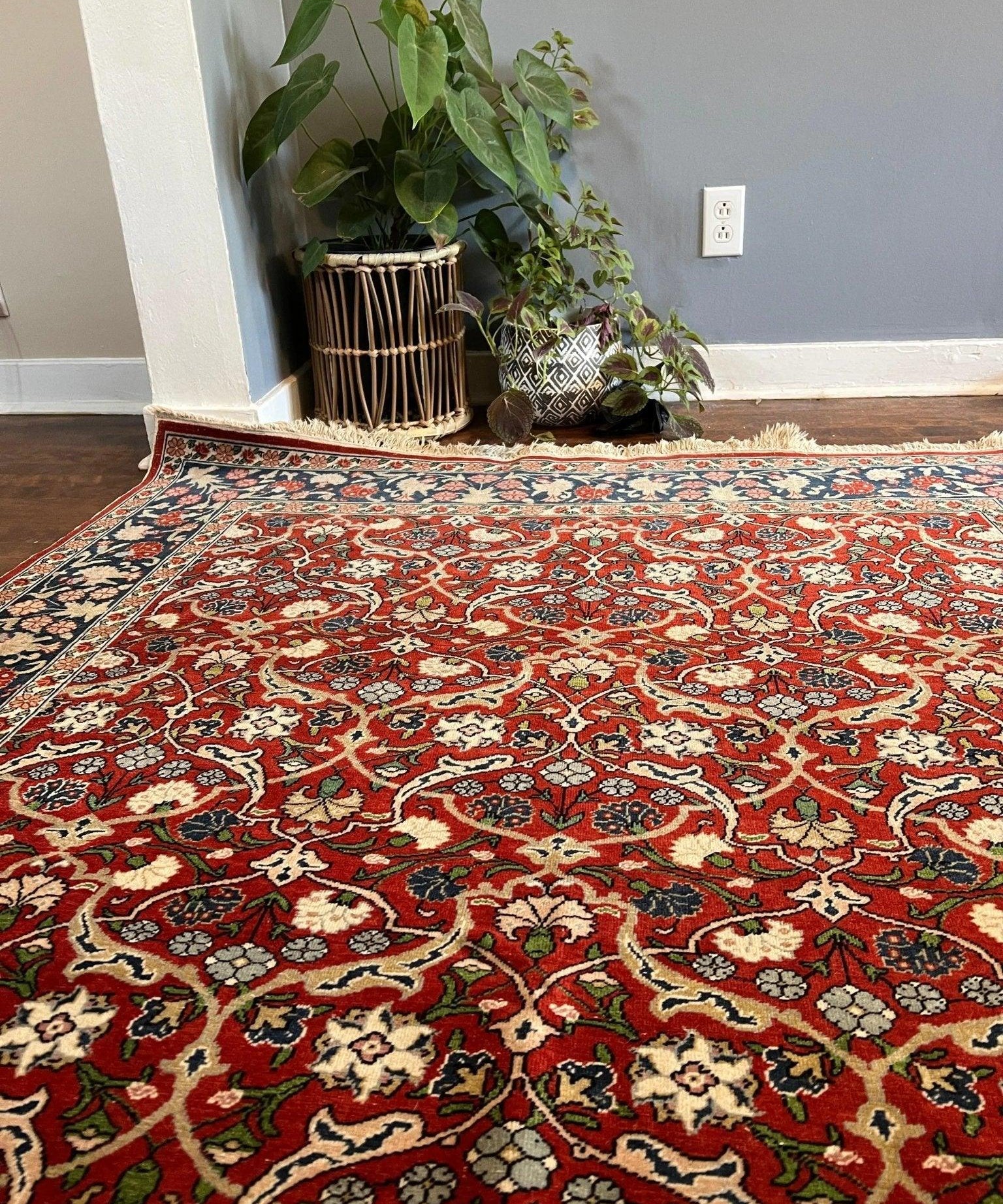 Red floral area rug with ornate medallion pattern and blue border, laid on floor