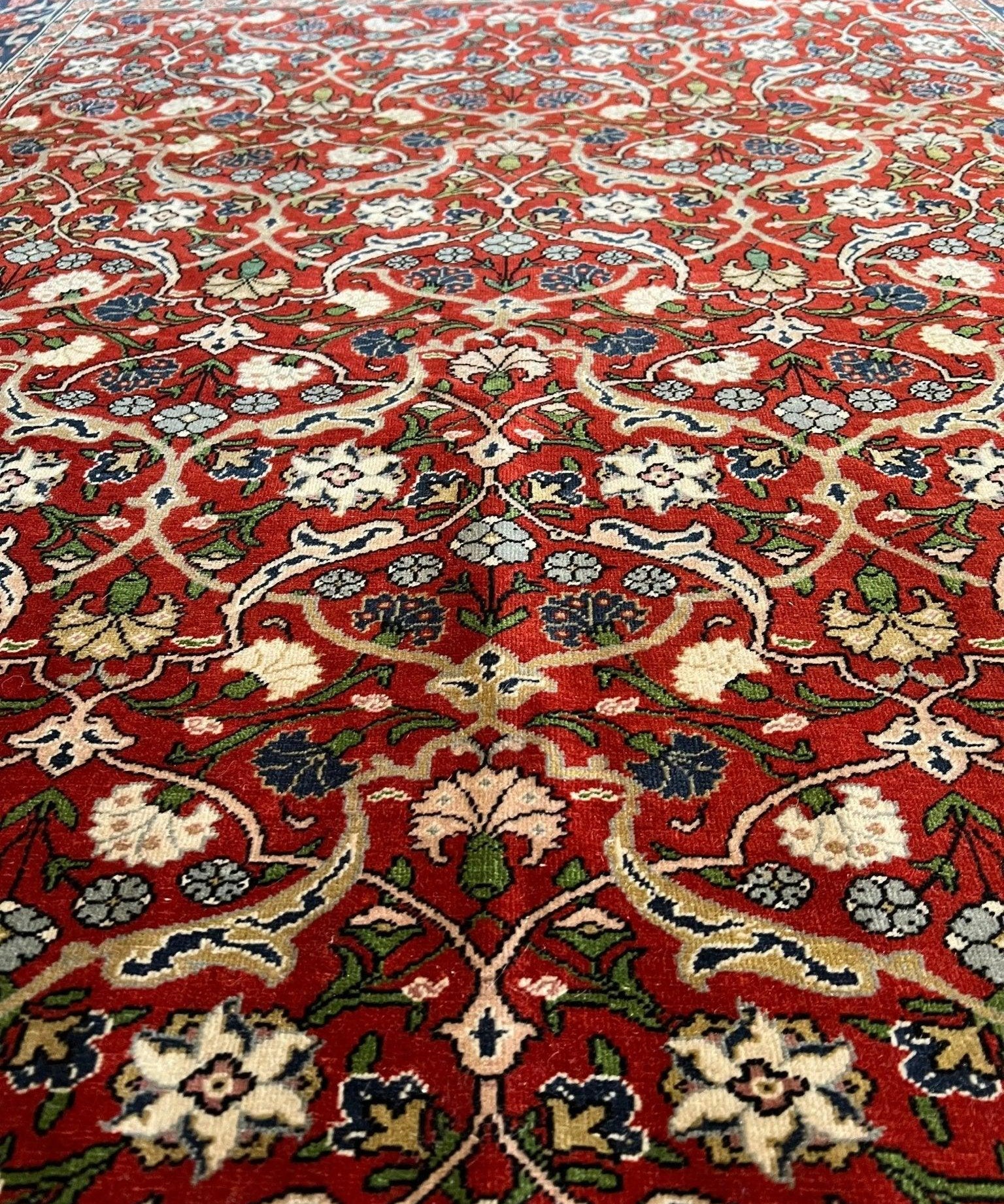 Red Persian-style rug with repeating medallion pattern and cream border detailing