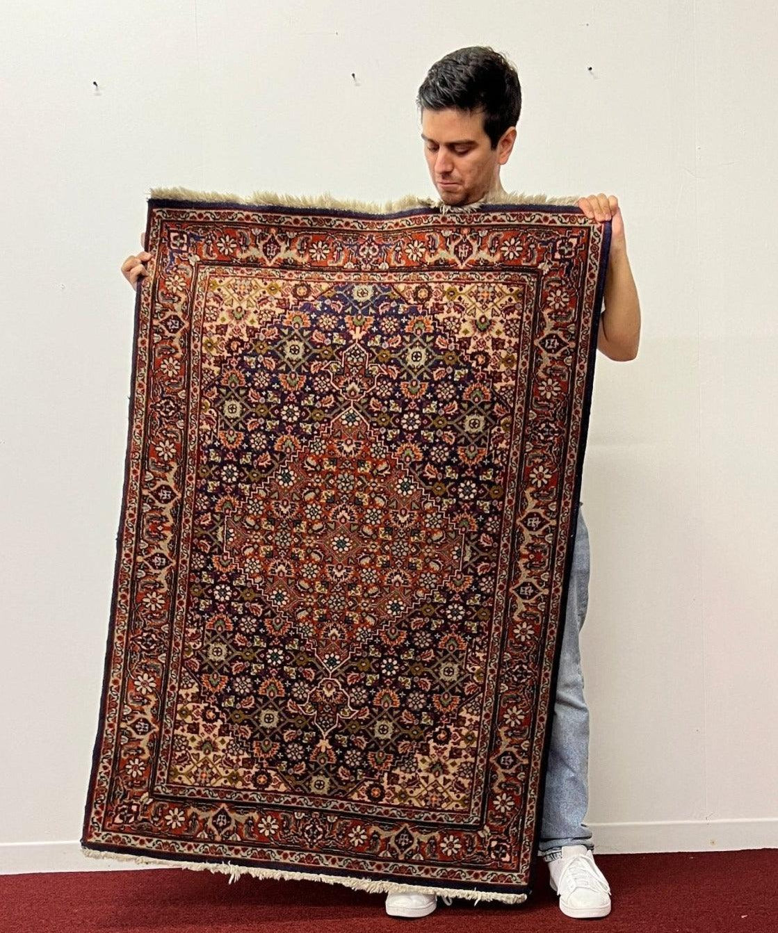 Persian Tabriz rug with red field, blue medallion, and ornate border
