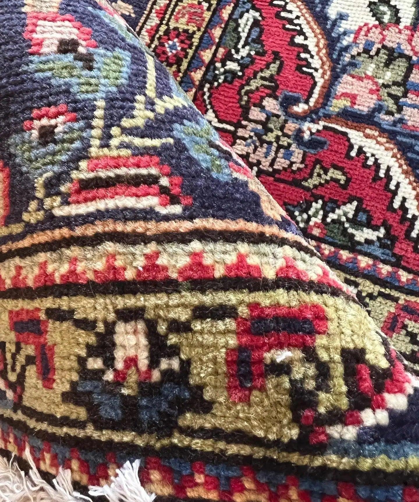 Textile close-up of Persian Tabriz-style rug, multicolor pattern with fringed edge