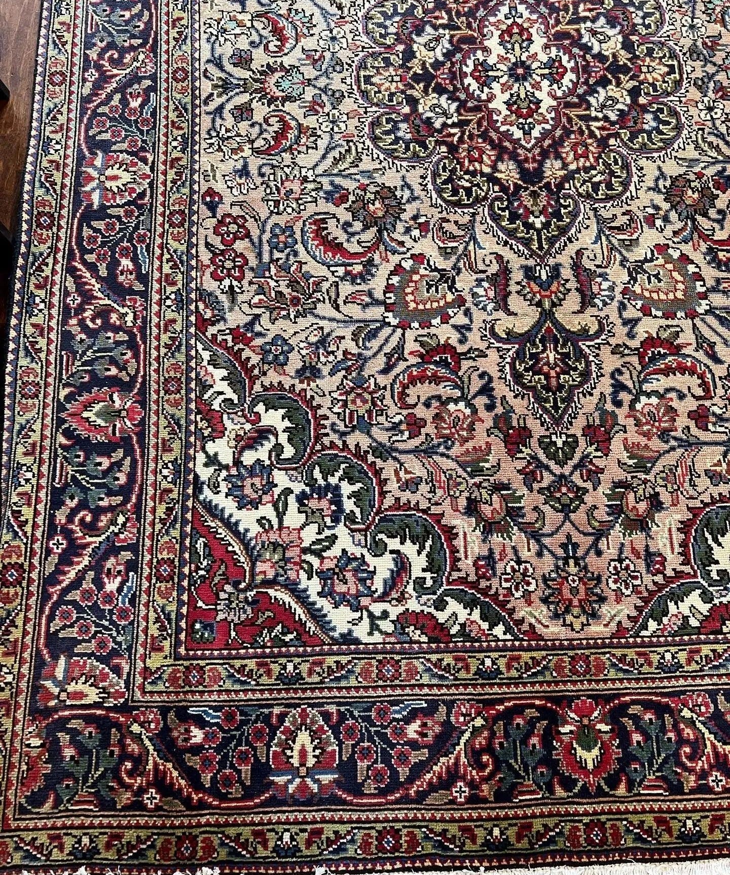 Persian Tabriz-style rug corner with detailed floral scrollwork and central medallion, light