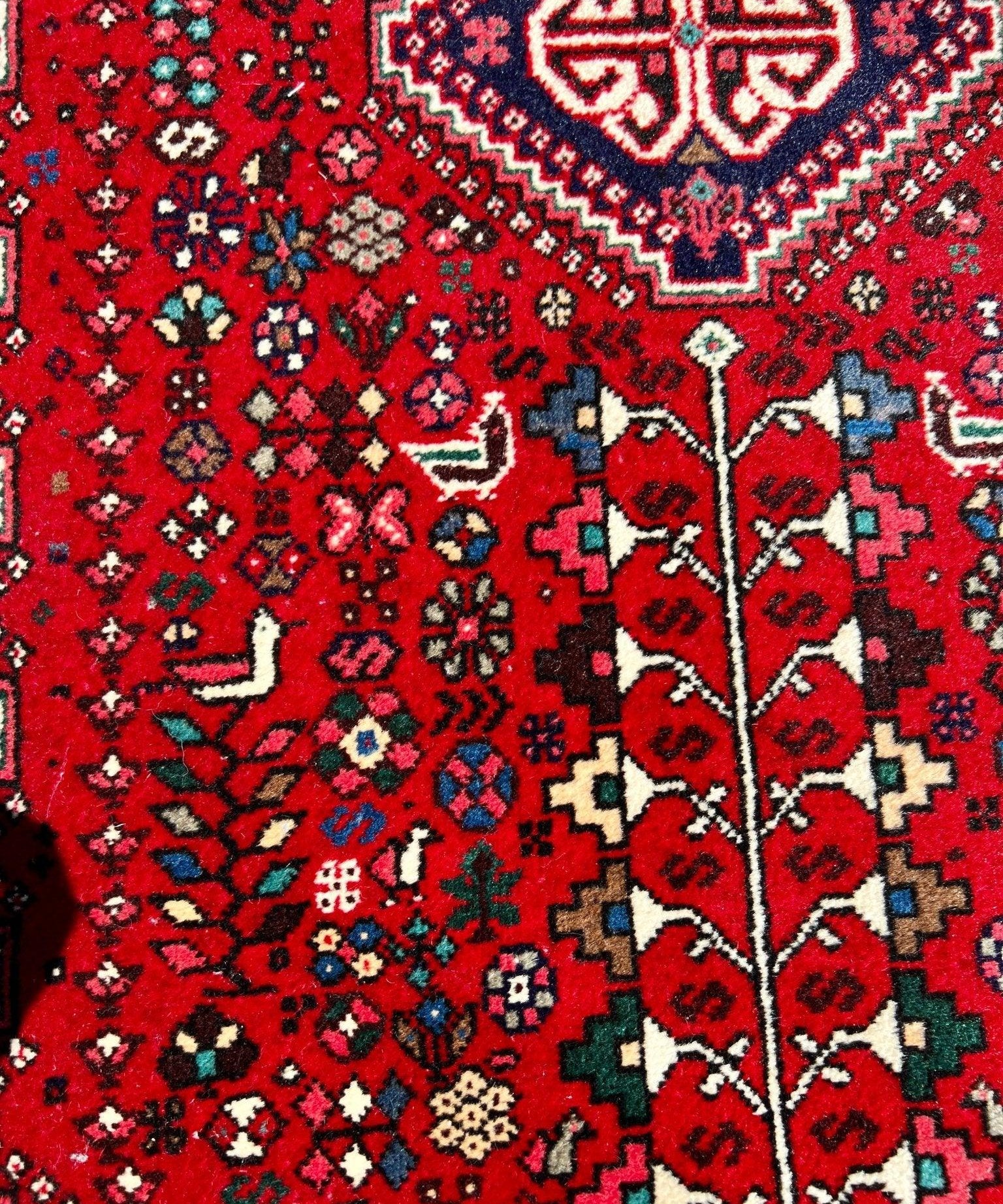 Persian Abadeh rug close-up, red background with multicolor floral geometric motifs