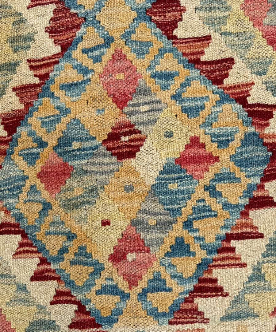 Kilim rug close-up with teal, blue, red, and yellow geometric shapes on cream