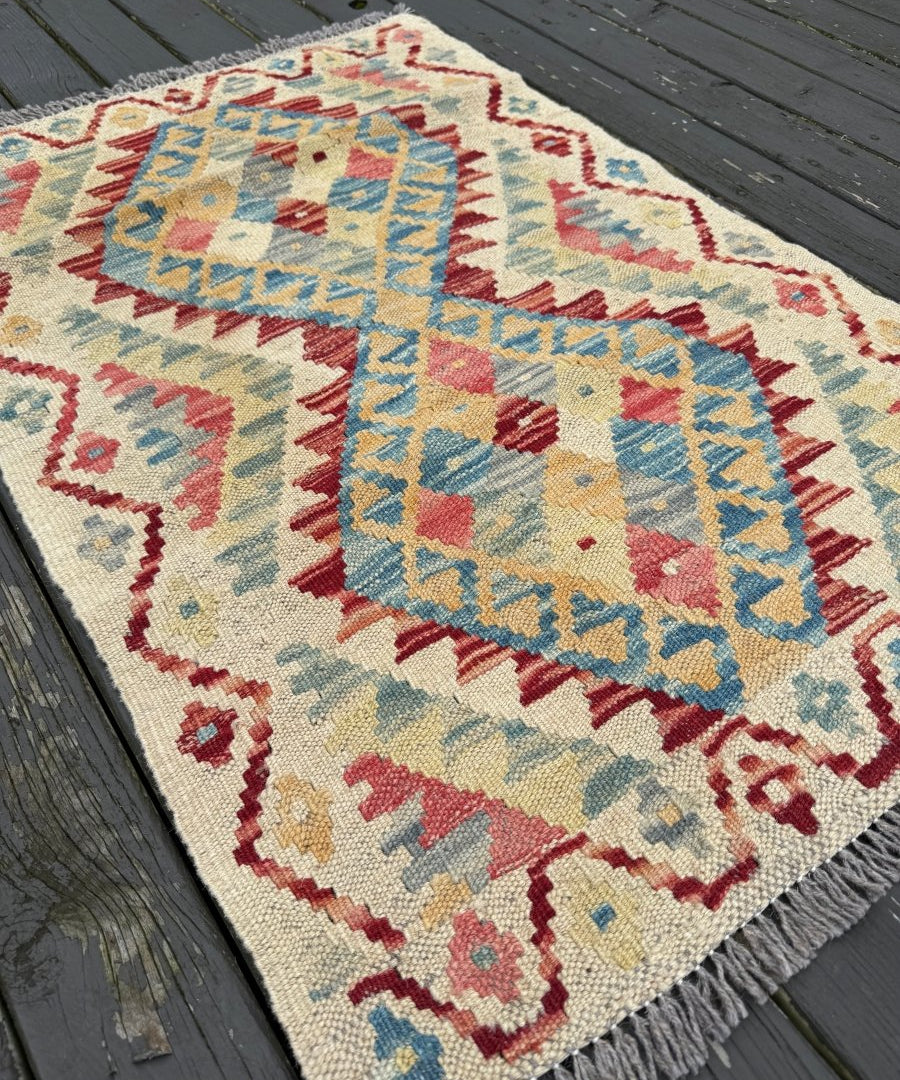 Afghan kilim rug, cream background with blue, red, and yellow geometric bands, short fringe