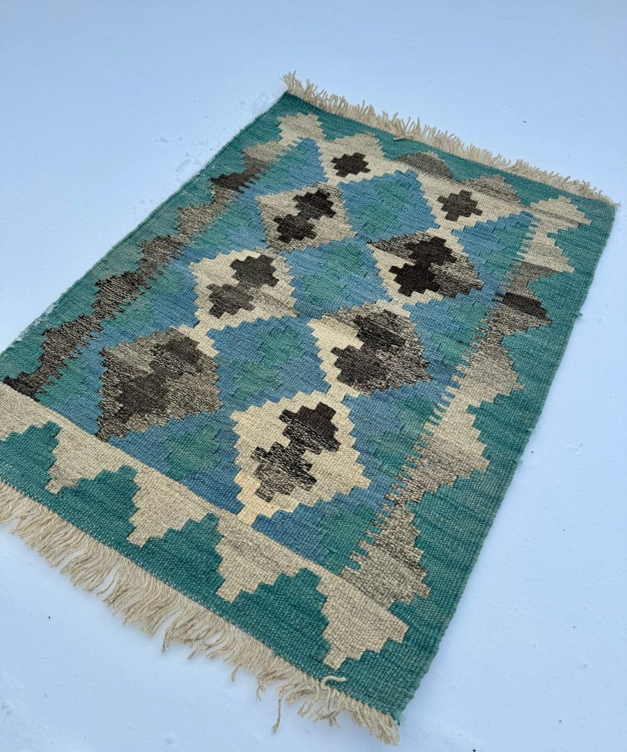 Kilim rug with teal, blue, cream and black geometric diamonds, short fringe border