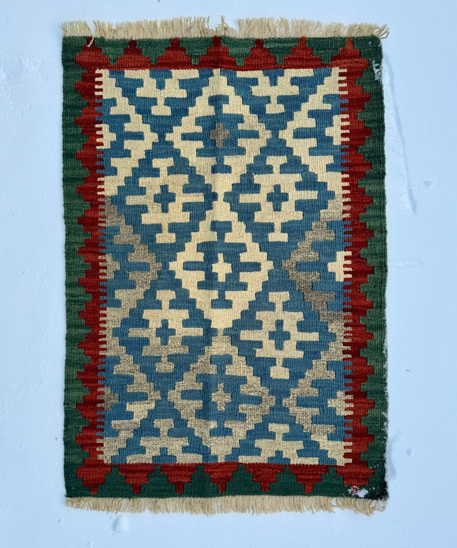 Tiny Persian Qashqai kilim rug with blue geometric pattern, red border, and green field