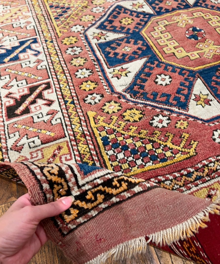 Rug edge close-up showing multicolor woven trim, cream pile, and short fringed border.