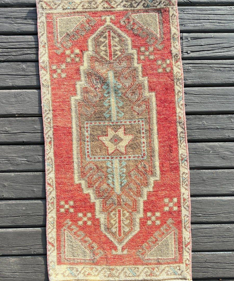 Turkish mini rug with red center and cream geometric medallion pattern, fringed edges.