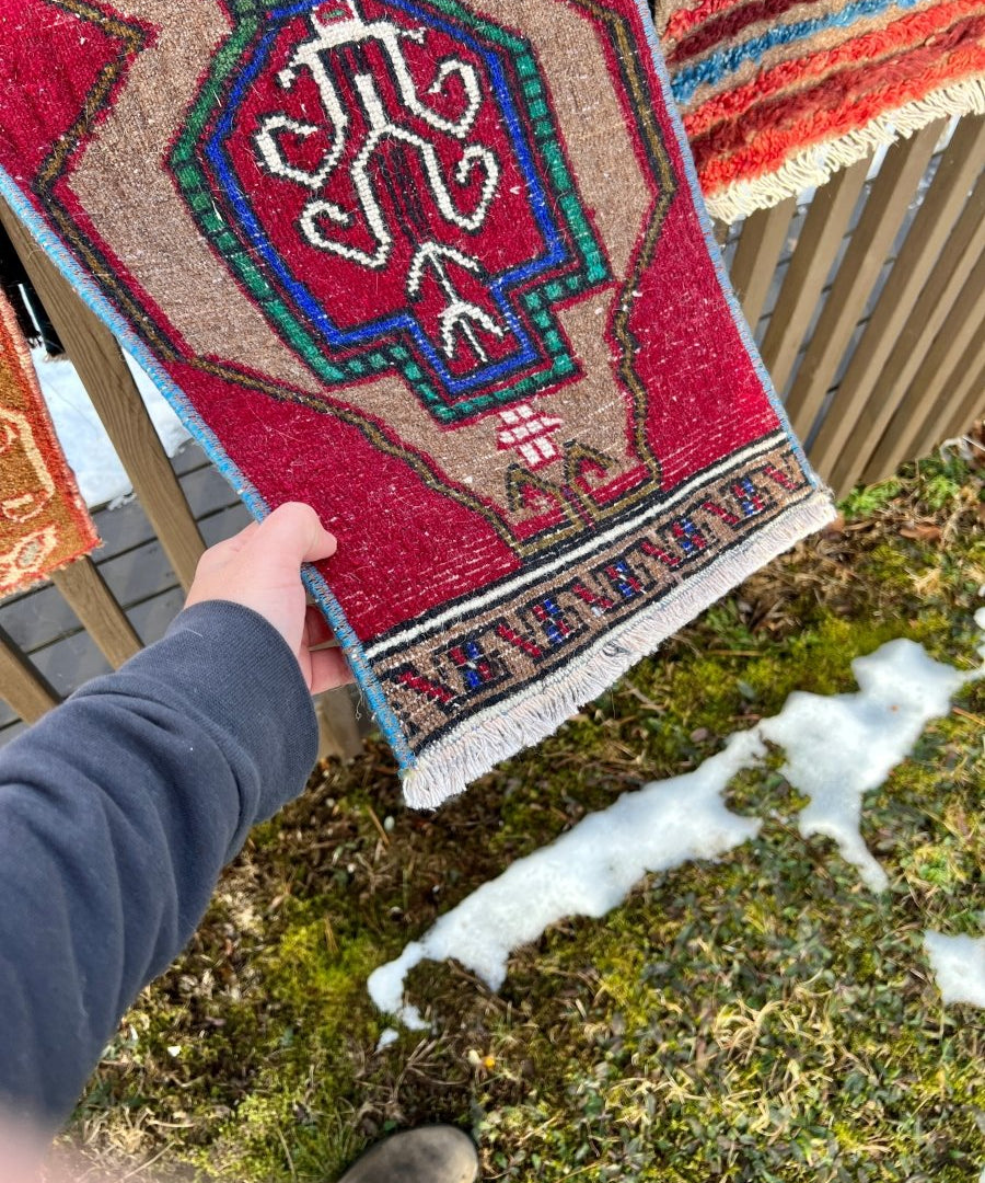 Turkish mini rug detail, red geometric medallion with blue outlines and fringed border