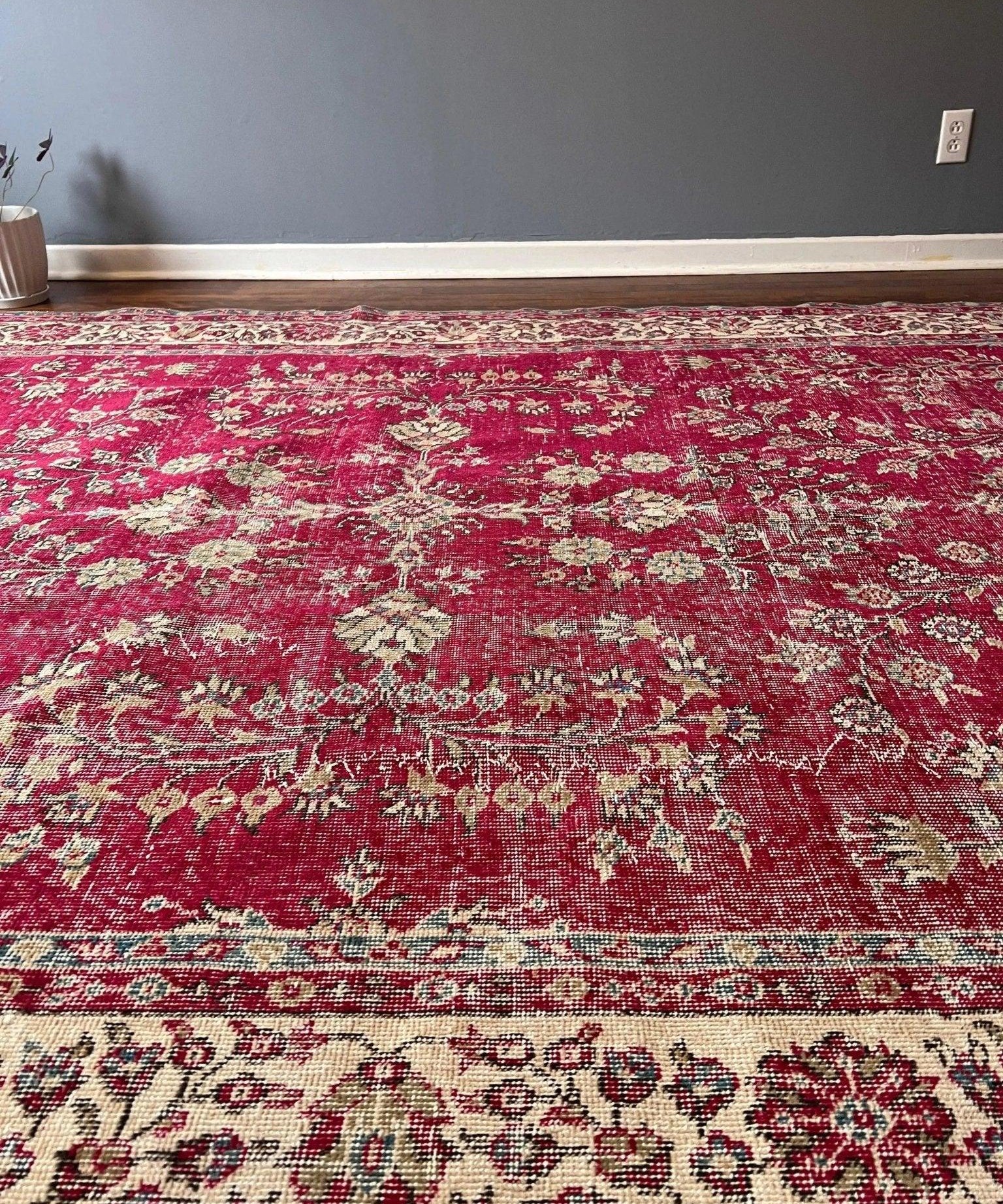 Red rug with cream floral motifs, central pattern, and decorative border strip