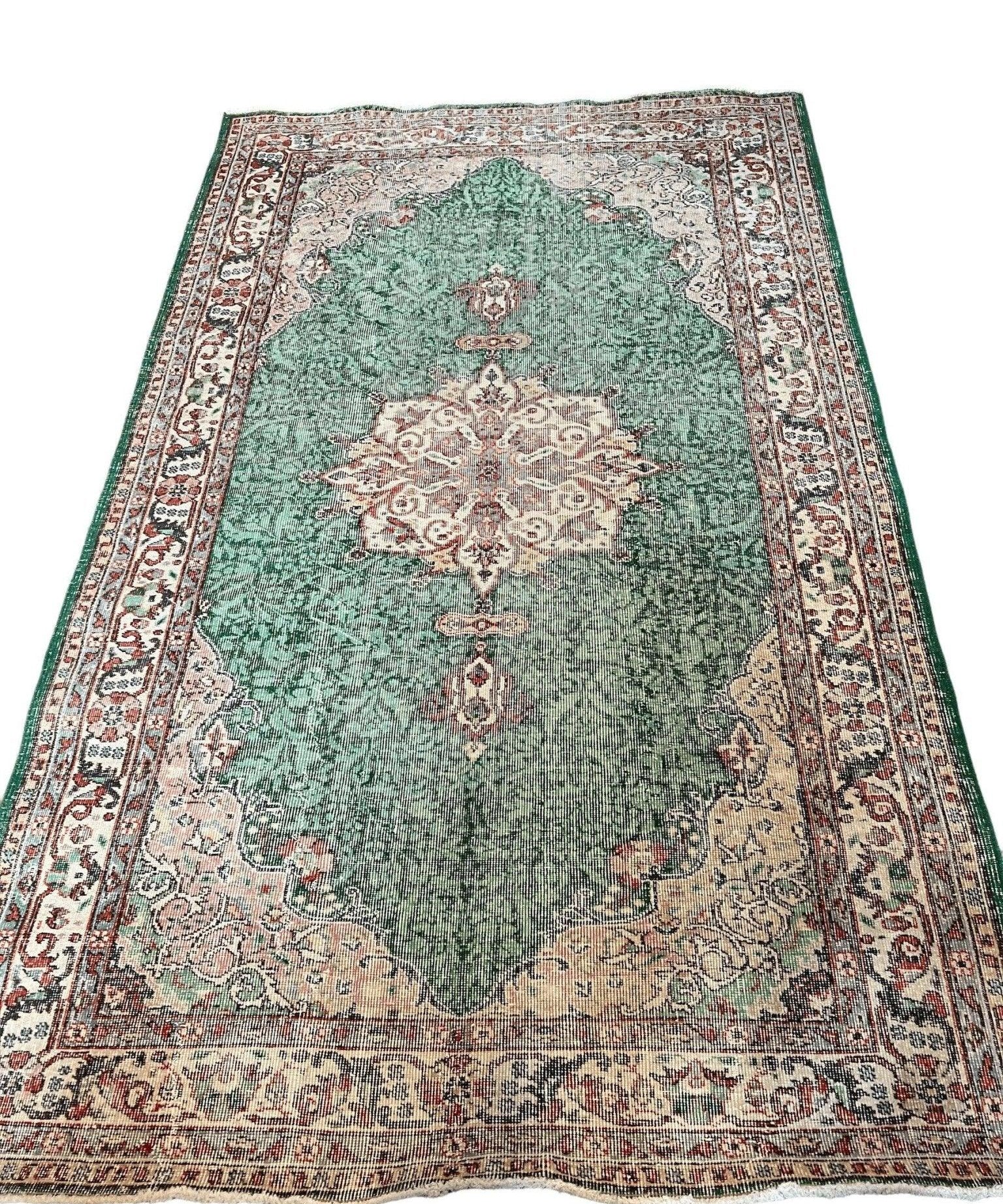 Green vintage rug with cream and rust medallion motifs and detailed border