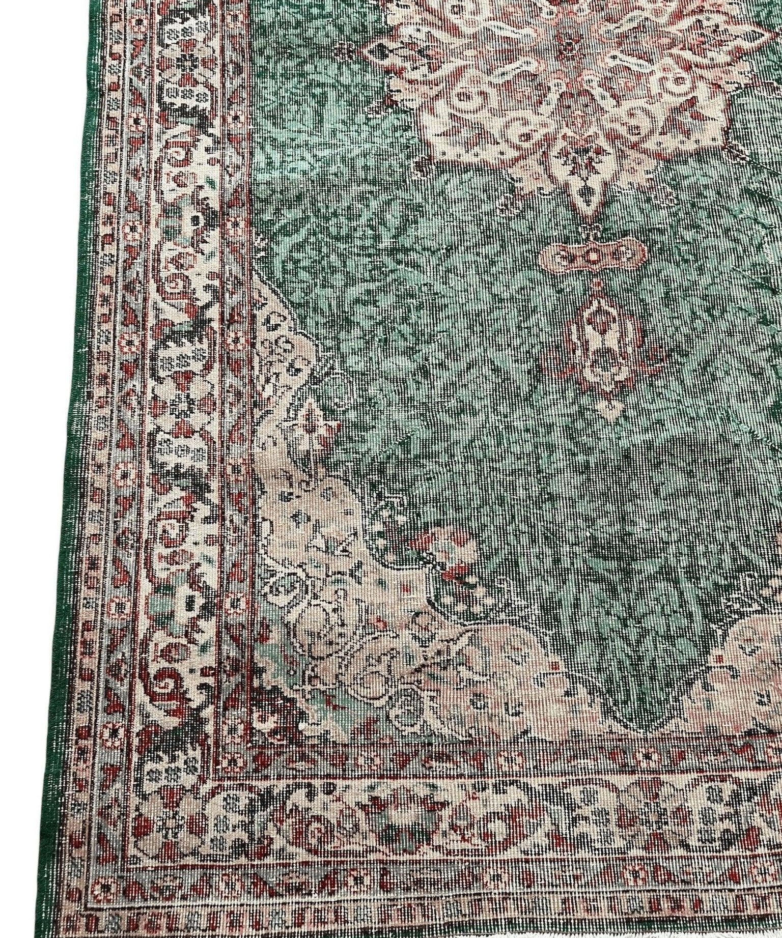 Green vintage rug corner with medallion, cream panel, and red patterned border