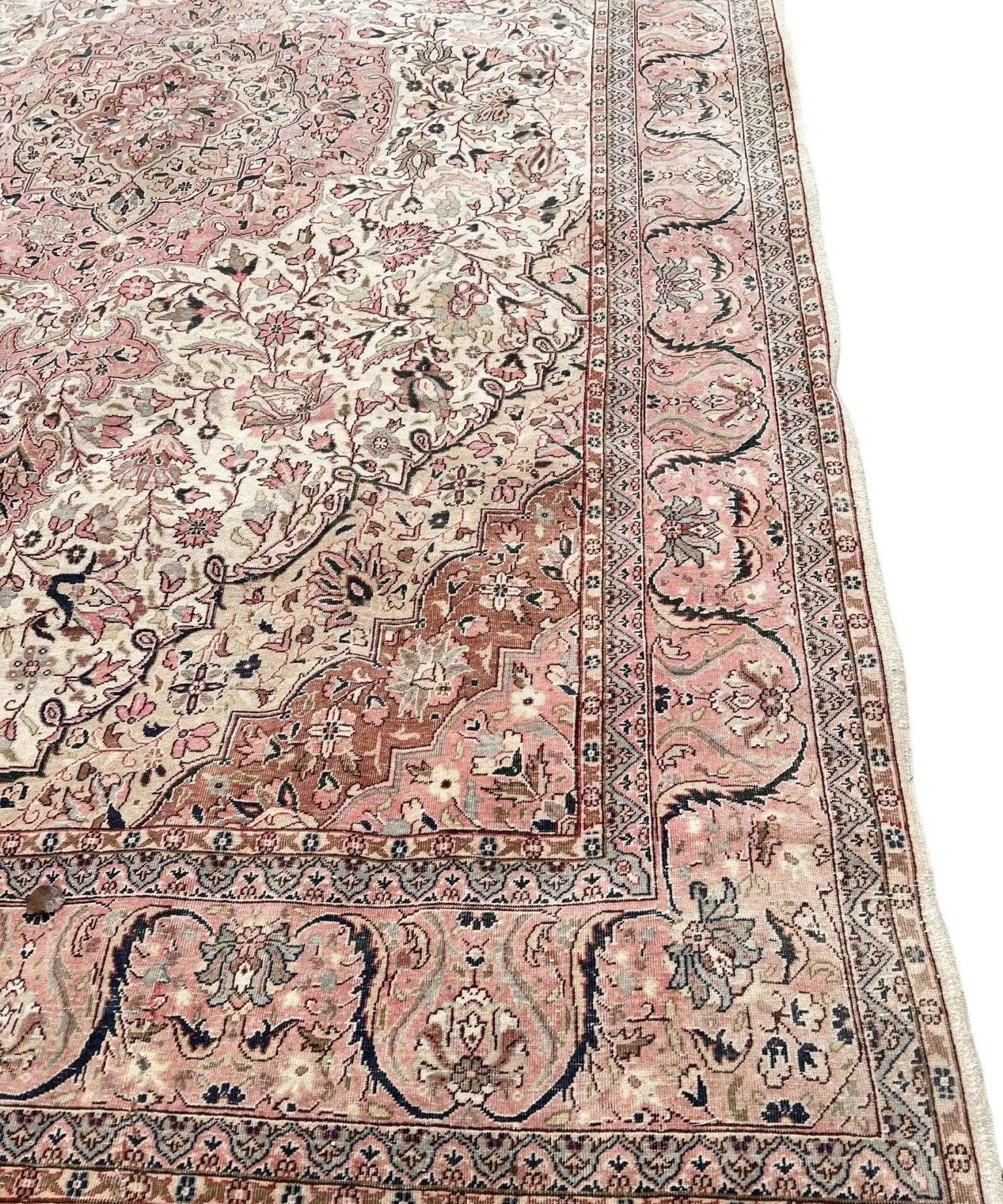 Corner view of vintage rug with cream ground, pink highlights, and dark navy border