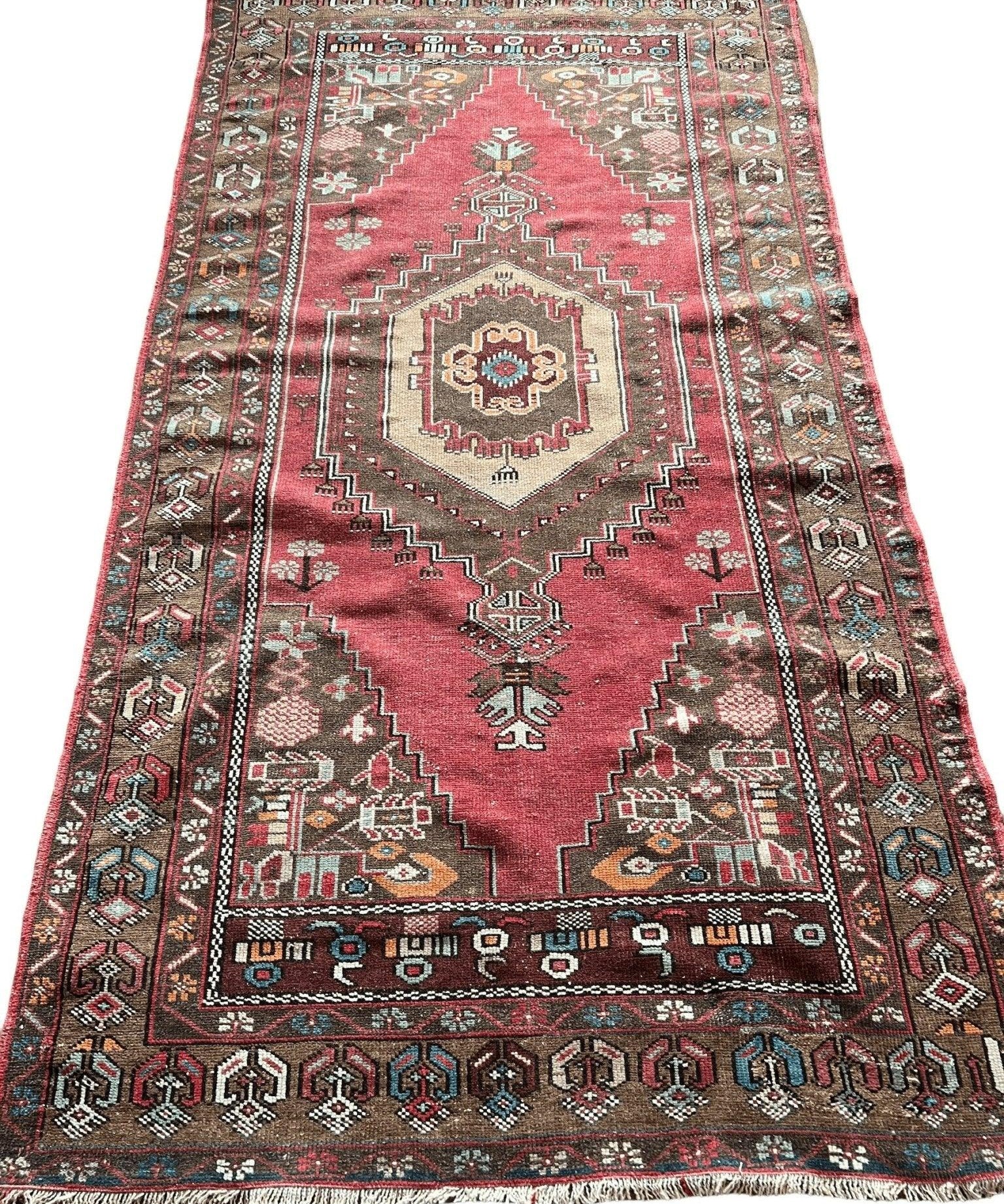 Red Turkish-style area rug with central medallion, ornate geometric panels, and fringe