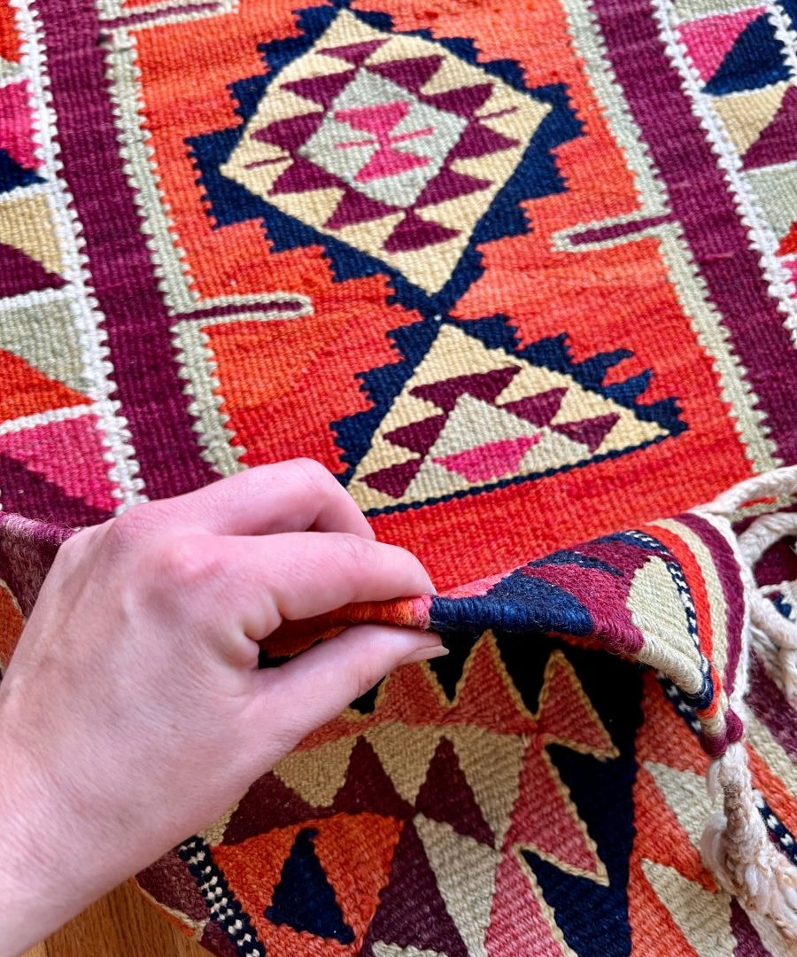 Close-up of red tribal runner rug edge with diamond motifs and multicolor woven texture